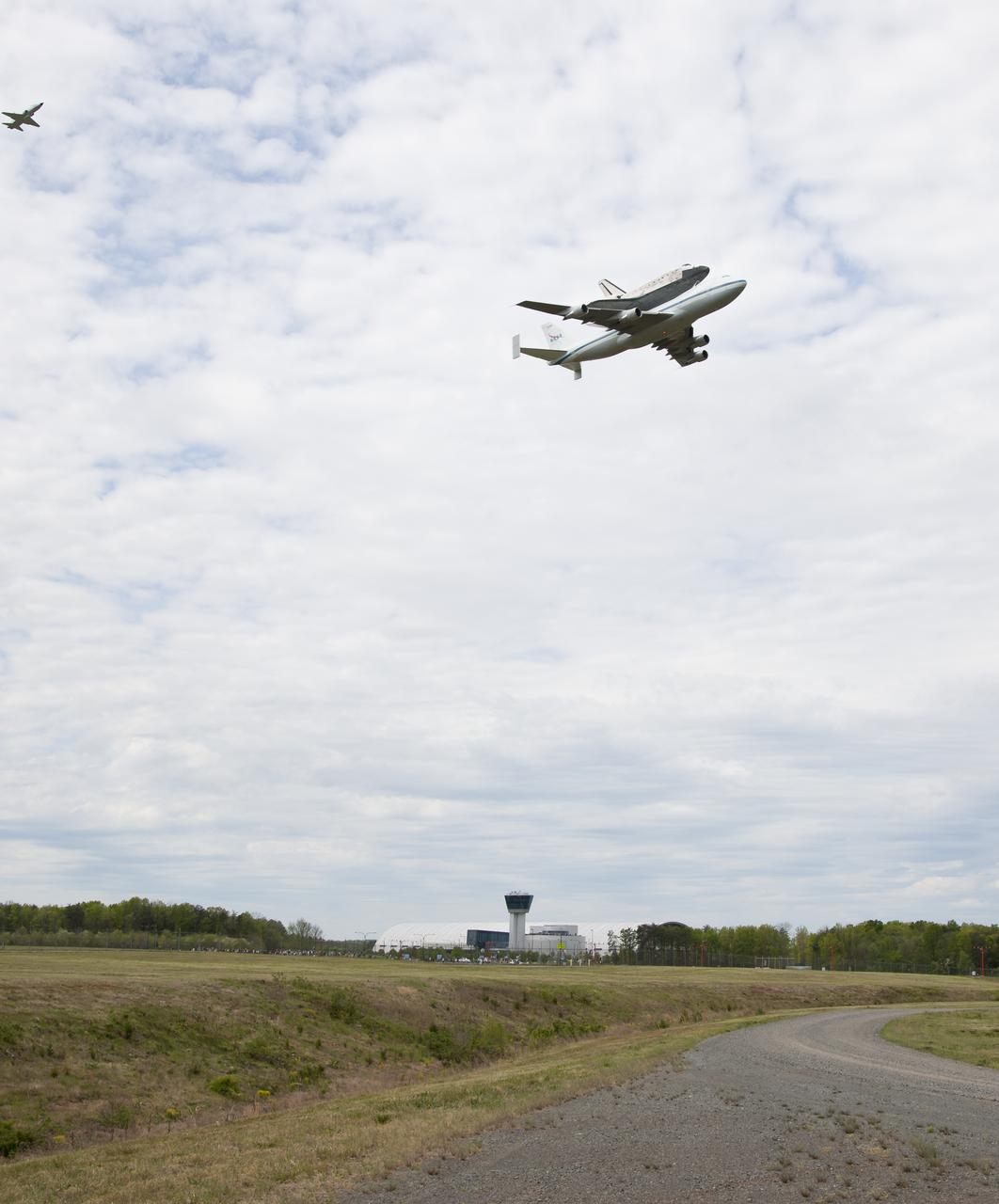 Space shuttle Discovery, mounted atop a NASA 747 Shuttle Carrier Aircraft (SCA) flies over the Steven F. Udvar-Hazy Center, Tuesday, April 17, 2012, in Washington. Discovery, the first orbiter retired from NASA’s shuttle fleet, completed 39 missions, spent 365 days in space, orbited the Earth 5,830 times, and traveled 148,221,675 miles. NASA will transfer Discovery to the National Air and Space Museum to begin its new mission to commemorate past achievements in space and to educate and inspire future generations of explorers. Photo Credit: (NASA/Smithsonian Institution/Dane Penland)