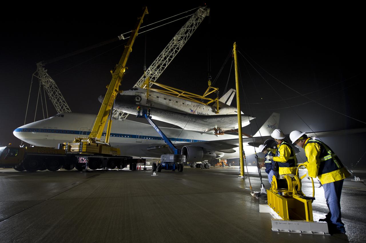 Workers monitor the lift of the space shuttle Discovery from the the NASA 747 Shuttle Carrier Aircraft (SCA) at Washington Dulles International Airport, Thursday, April 19, 2012, in Sterling, VA.  Discovery, the first orbiter retired from NASA’s shuttle fleet, completed 39 missions, spent 365 days in space, orbited the Earth 5,830 times, and traveled 148,221,675 miles. NASA will transfer Discovery to the National Air and Space Museum to begin its new mission to commemorate past achievements in space and to educate and inspire future generations of explorers. Photo Credit: (NASA/Bill Ingalls)