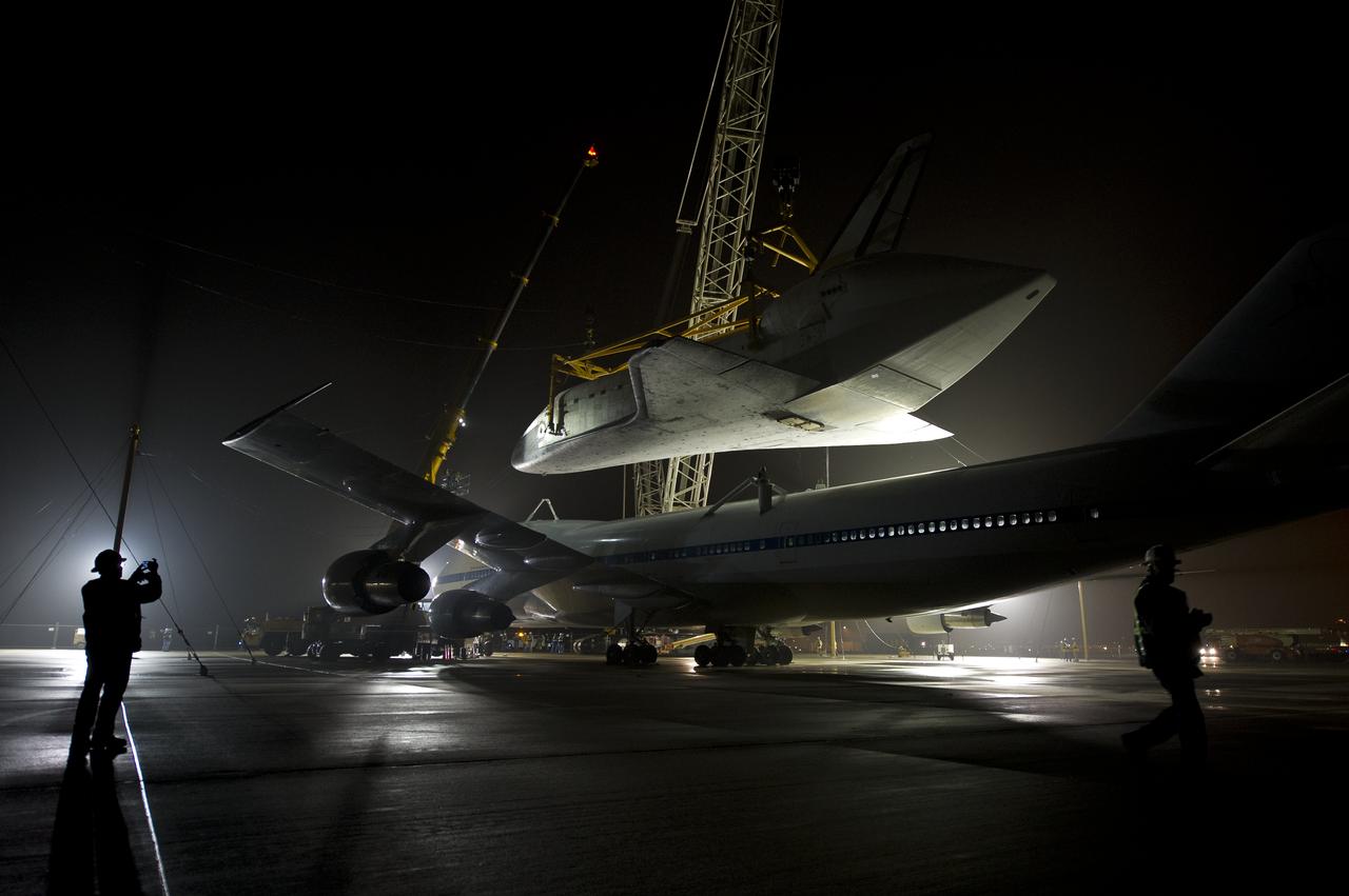 Workers monitor the lift of the space shuttle Discovery from the top of the NASA 747 Shuttle Carrier Aircraft (SCA) at Washington Dulles International Airport, Thursday, April 19, 2012, in Sterling, VA.  Discovery, the first orbiter retired from NASA’s shuttle fleet, completed 39 missions, spent 365 days in space, orbited the Earth 5,830 times, and traveled 148,221,675 miles. NASA will transfer Discovery to the National Air and Space Museum to begin its new mission to commemorate past achievements in space and to educate and inspire future generations of explorers. Photo Credit: (NASA/Bill Ingalls)