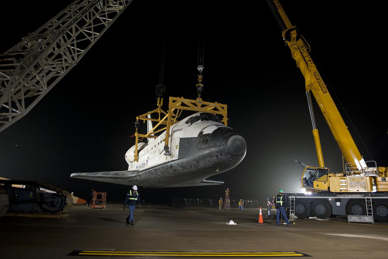 The space shuttle Discovery is suspended from a sling held by two cranes after the NASA 747 Shuttle Carrier Aircraft (SCA) was pushed back from underneath at Washington Dulles International Airport, Thursday, April 19, 2012, in Sterling, VA.  Discovery, the first orbiter retired from NASA’s shuttle fleet, completed 39 missions, spent 365 days in space, orbited the Earth 5,830 times, and traveled 148,221,675 miles. NASA will transfer Discovery to the National Air and Space Museum to begin its new mission to commemorate past achievements in space and to educate and inspire future generations of explorers. Photo Credit: (NASA/Bill Ingalls)