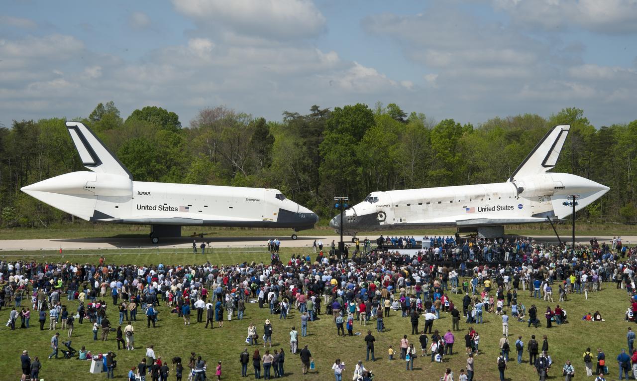 Space Shuttles Enterprise, left, and Discovery meet nose-to-nose at the beginning of a transfer ceremony at the Smithsonian's Steven F. Udvar-Hazy Center, Thursday, April 19, 2012, in Chantilly, Va. Space shuttle Discovery, the first orbiter retired from NASA’s shuttle fleet, completed 39 missions, spent 365 days in space, orbited the Earth 5,830 times, and traveled 148,221,675 miles will take the place of Enterprise at the center to commemorate past achievements in space and to educate and inspire future generations of explorers at the center. Photo Credit: (NASA/Smithsonian Institution/Carolyn Russo)