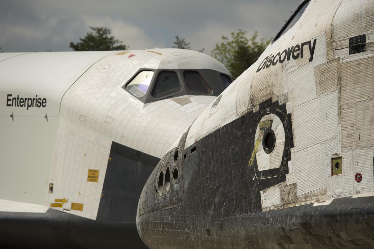 Space Shuttles Enterprise, left, and Discovery meet nose-to-nose during the a transfer ceremony at the Smithsonian's Steven F. Udvar-Hazy Center, Thursday, April 19, 2012, in Chantilly, Va. Space shuttle Discovery, the first orbiter retired from NASA’s shuttle fleet, completed 39 missions, spent 365 days in space, orbited the Earth 5,830 times, and traveled 148,221,675 miles will take the place of Enterprise at the center to commemorate past achievements in space and to educate and inspire future generations of explorers at the center. Photo Credit: (NASA/Carla Cioffi)