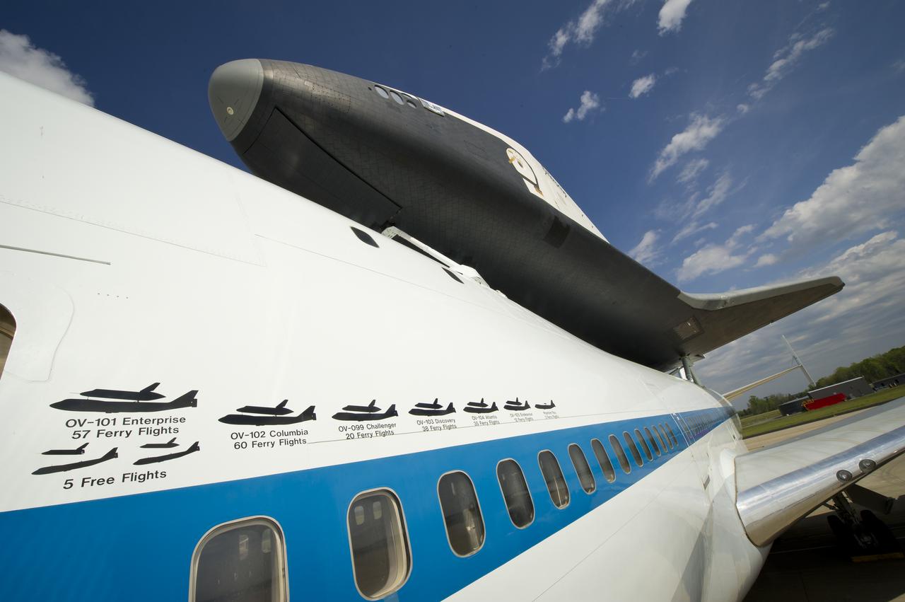The space shuttle Enterprise is seen mated on top of the NASA 747 Shuttle Carrier Aircraft (SCA) at Washington Dulles International Airport, Saturday, April 21, 2012, in Sterling, Va. Painted graphics line the side of NASA 905 depicting the various ferry flights the Shuttle Carrier Aircraft has supported during the Space Shuttle Program, including the tests using the space shuttle prototype Enterprise.  Space Shuttle Transition and Retirement engineers Saturday completed the final steps to ready Space Shuttle Enterprise for its flight to New York’s John F. Kennedy International Airport while managers continue to evaluate the expected weather that has postponed delivery past Monday. Enterprise, the first orbiter built for the Space Shuttle Program, was used primarily for ground and flight tests within the atmosphere. The initial testing period named Approach and Landing Test (ALT) included a flight on February 18, 1977 atop a Shuttle Carrier Aircraft (SCA) to measure structural loads and ground handling and braking characteristics of the mated system. Enterprise will go on permanent display at the Intrepid Sea Air and Space Museum in New York in June. Photo Credit:  (NASA/Bill Ingalls)