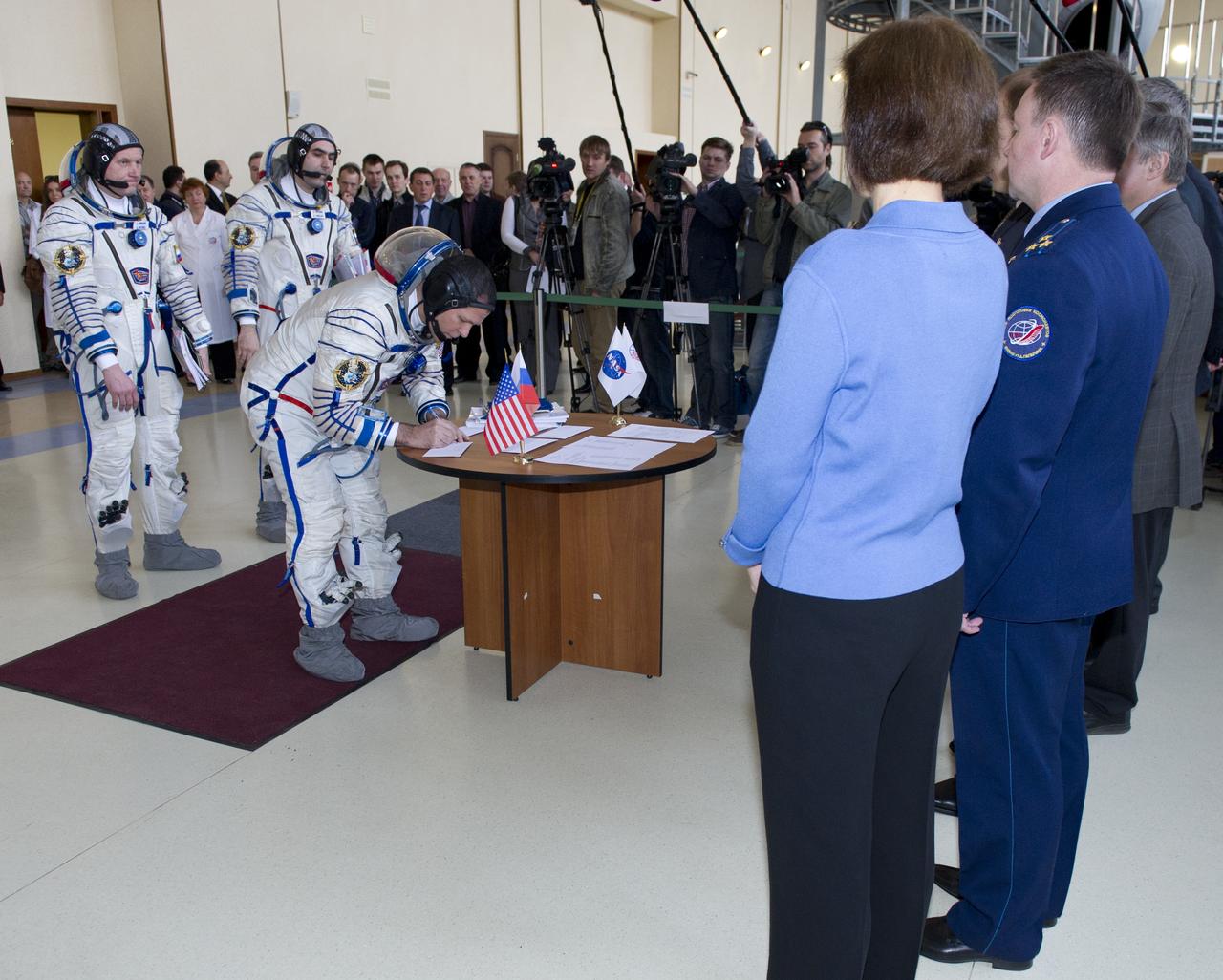 Expedition 31 NASA backup crew member Kevin Ford signs for his Soyuz vehicle simulation test card before senior officials at the Gagarin Cosmonaut Training Center, Monday, April 23, 2012 in Star City, Russia, while his fellow crew members Oleg Novitskiy (far left) and Evgeny Tarelkin look on.  Expedition 31 prime crew members commander Gennady Padalka, flight engineers Joe Acaba and Sergei Revin practiced similar scenarios nearby in advance of their final approval for launch to the International Space Station, scheduled for May 15, 2012.  Photo Credit:  (NASA/Carla Cioffi)