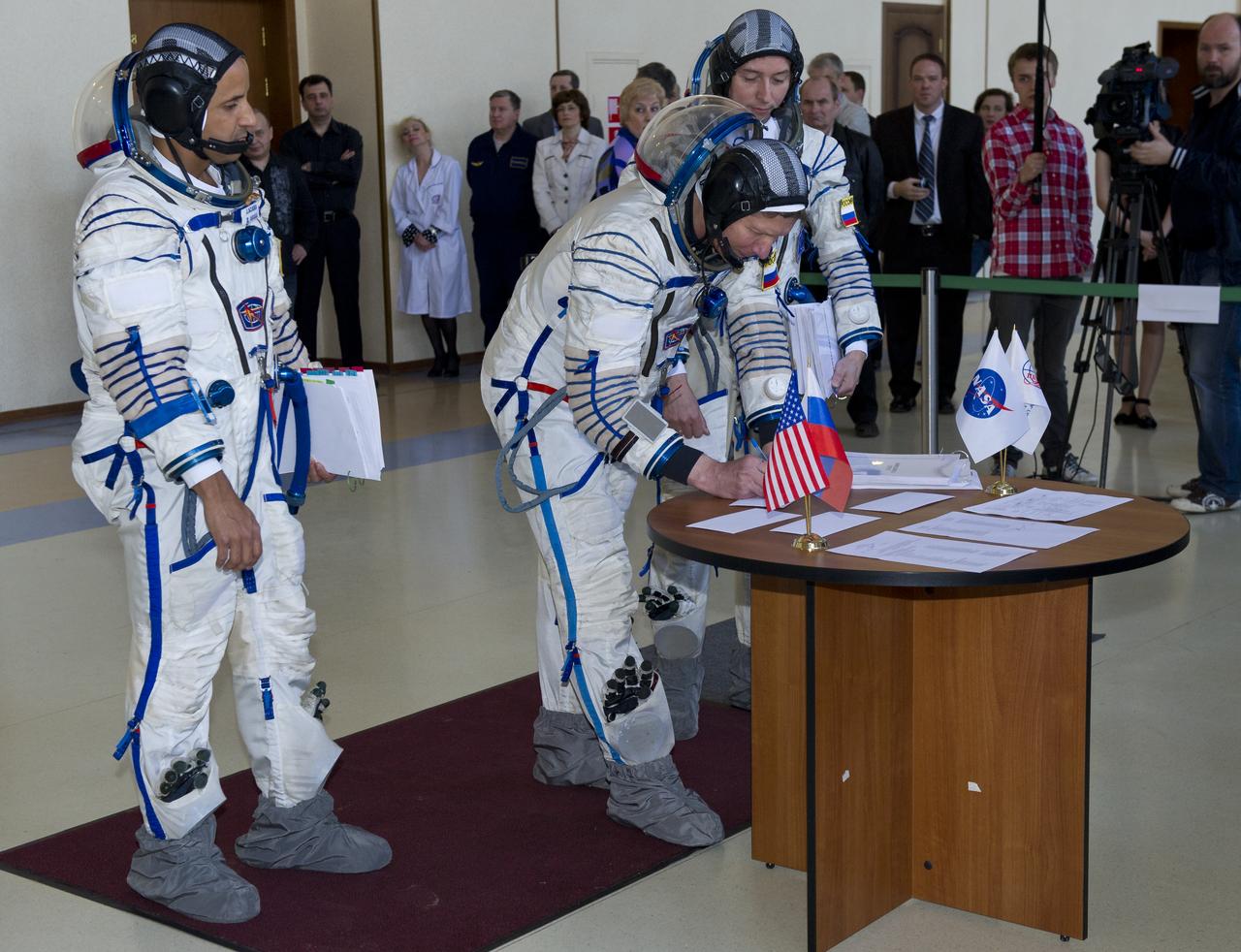 Expedition 31 Soyuz Commander Gennady Padalka signs for his Soyuz vehicle simulation test card before senior officials at the Gagarin Cosmonaut Training Center, Tuesday, April 24, 2012 in Star City, Russia, while his fellow crew members NASA flight engineer Joe Acaba, left, and flight engineer Sergei Revin look on. Padalka, Acaba and Revin are set to launch to the International Space Station May 15 from the Baikonur Cosmodrome in Kazakhstan. Photo Credit: (NASA/Carla Cioffi)