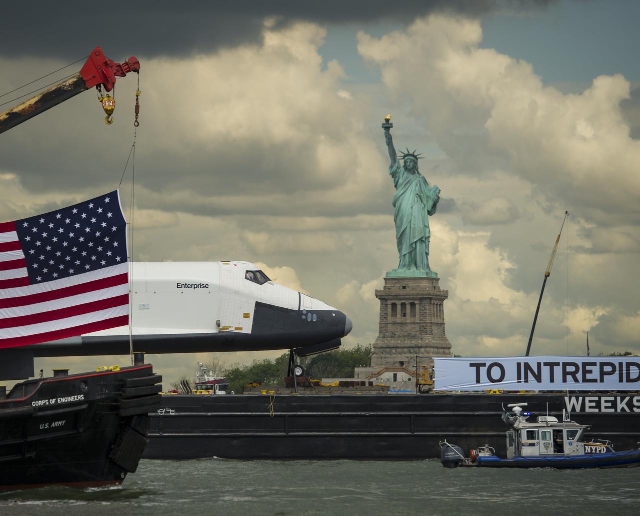 The space shuttle Enterprise, atop a barge,  passes the Statue of Liberty in New York on its way to the Intrepid Sea, Air and Space Museum where it will be permanently displayed, Wednesday, June 6, 2012. Photo Credit: (NASA/Bill Ingalls)