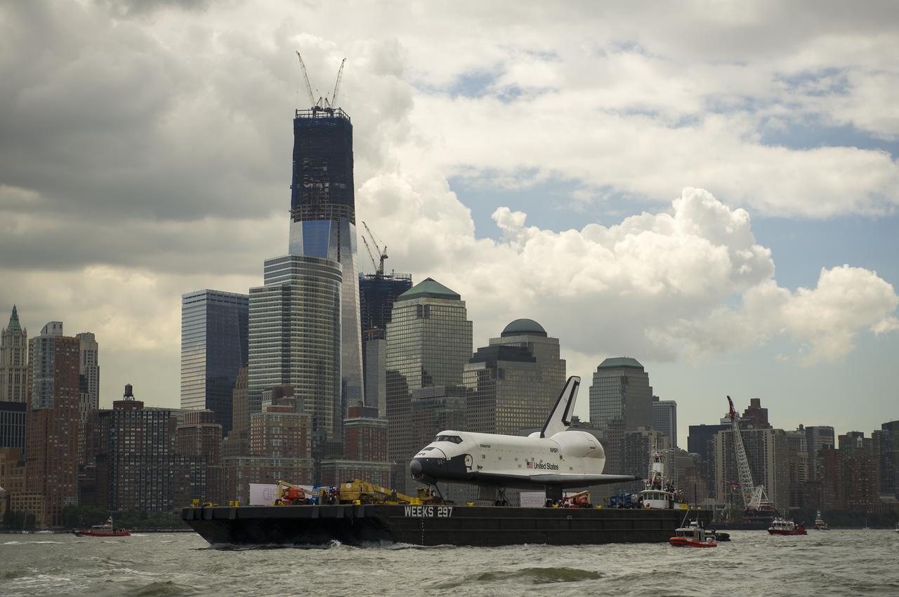 The space shuttle Enterprise is towed by barge up the Hudson River in New York with the World Trade Center's Freedom Tower in the background while on it's way to the Intrepid Sea, Air and Space Museum where it will be permanently displayed, Wednesday, June 6, 2012. Photo Credit: (NASA/Bill Ingalls)