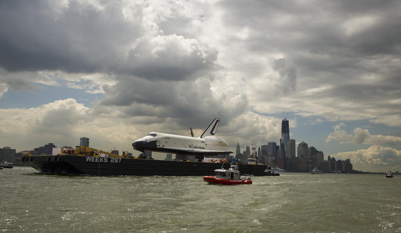 The space shuttle Enterprise is towed by barge up the Hudson River in New York with the World Trade Center's Freedom Tower in the background while on it's way to the Intrepid Sea, Air and Space Museum where it will be permanently displayed, Wednesday, June 6, 2012. Photo Credit: (NASA/Bill Ingalls)