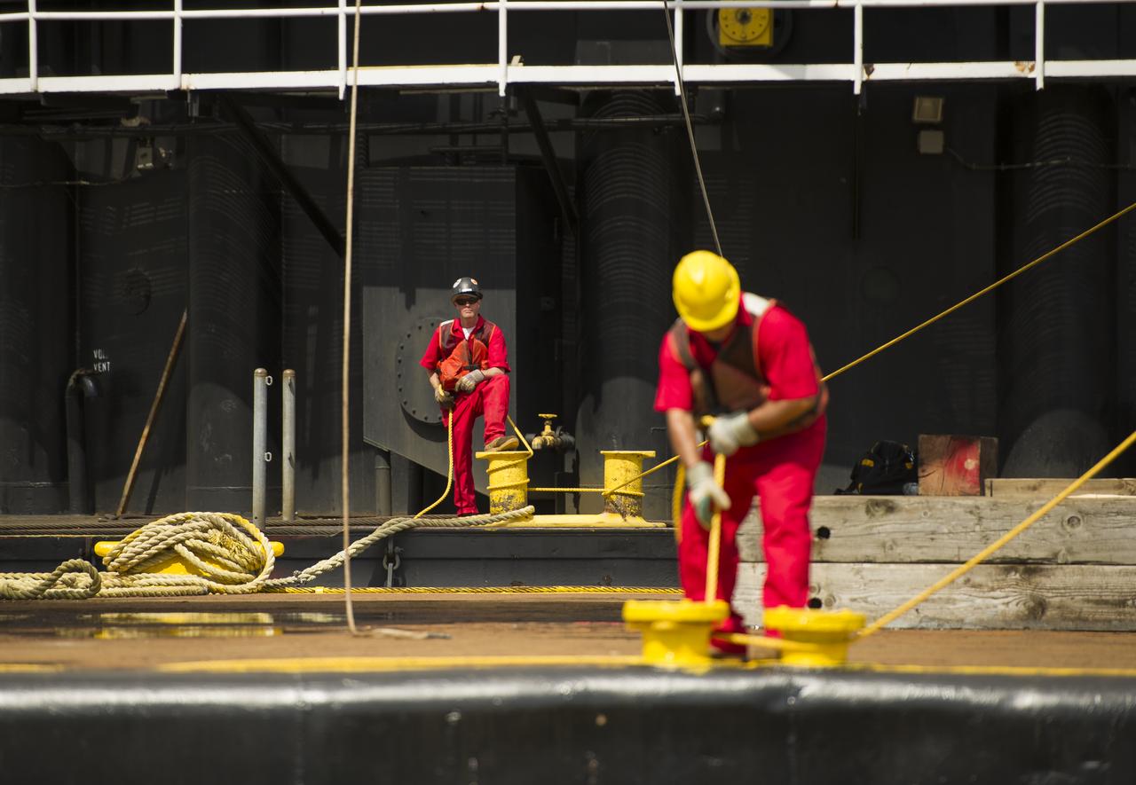 Workers control support ropes from the space shuttle Enterprise in preparation to lift it off of a barge and onto the Intrepid Sea, Air and Space Museum where it will be permanently displayed, Wednesday, June 6, 2012 in New York. Photo Credit: (NASA/Bill Ingalls)