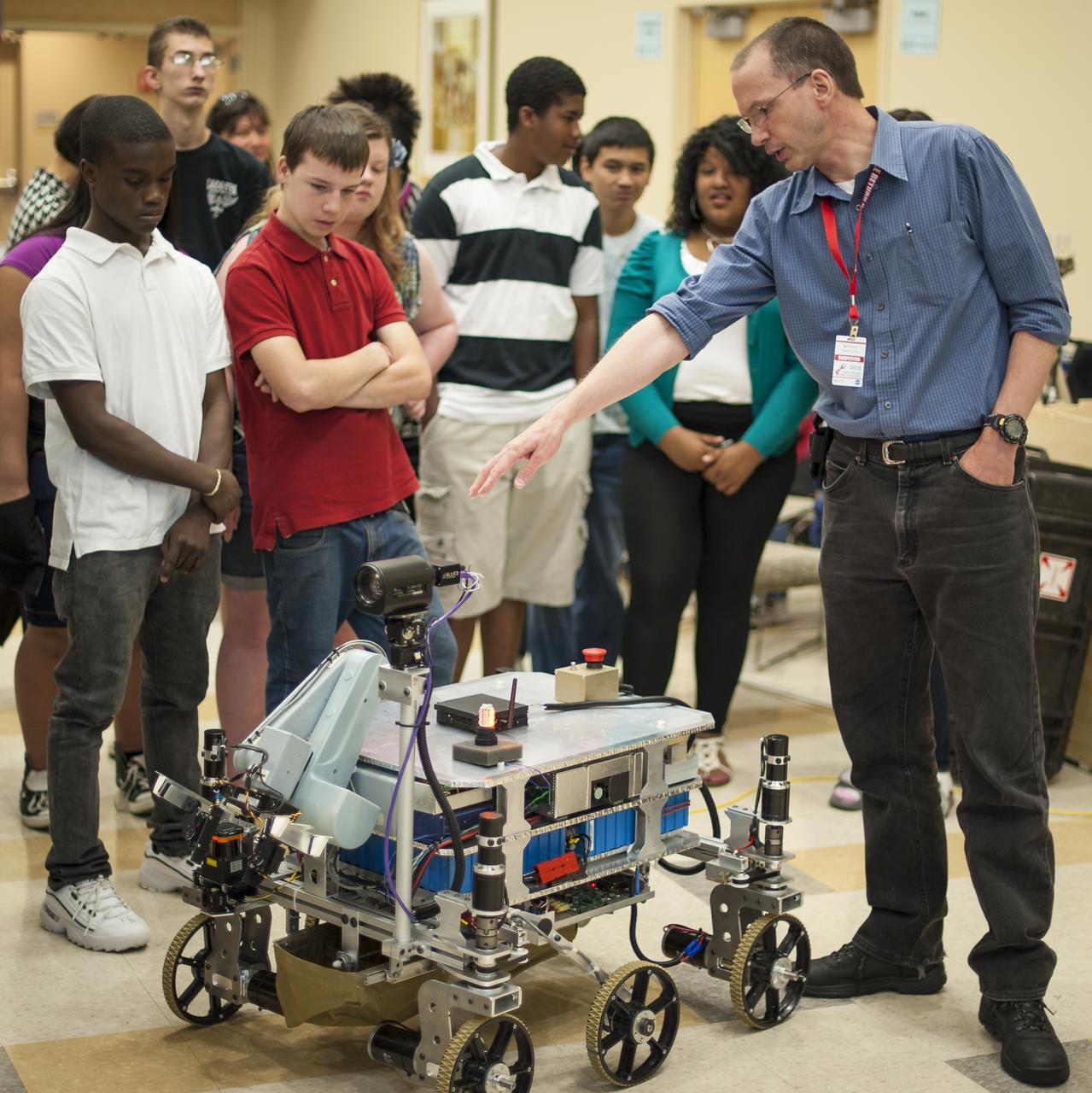 Intrepid Systems Team member Mark Curry, right, answers questions from 8th grade Sullivan Middle School (Mass.) students about his robot named "MXR - Mark's Exploration Robot" on Friday, June 15, 2012, at the Worcester Polytechnic Institute (WPI) in Worcester, Mass.  Curry's robot team will compete for a $1.5 million NASA prize in the NASA-WPI Sample Return Robot Centennial Challenge at WPI.  Teams have been challenged to build autonomous robots that can identify, collect and return samples.  NASA needs autonomous robotic capability for future planetary exploration. Photo Credit: (NASA/Bill Ingalls)
