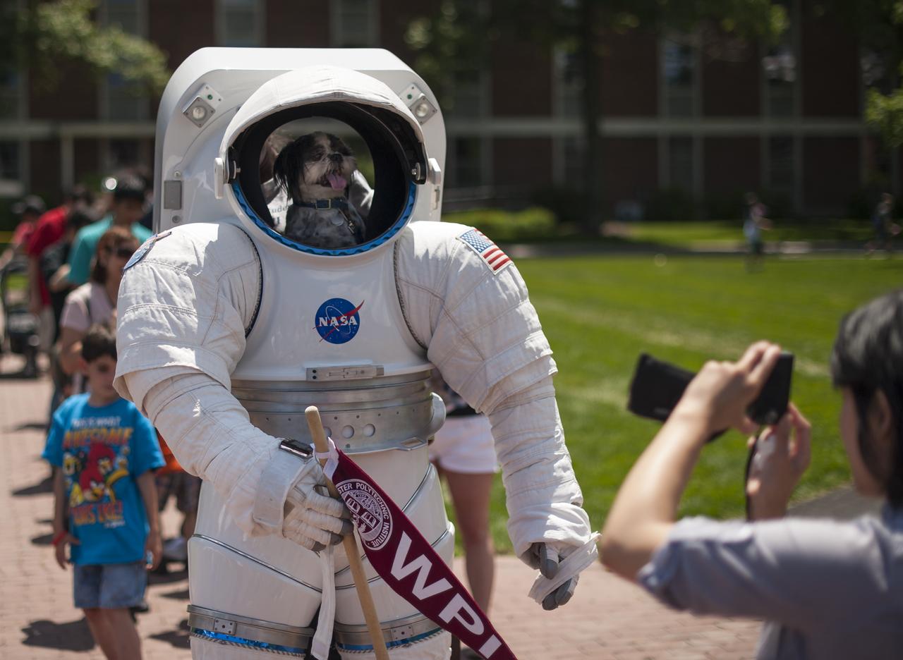 Visitors, some with their dogs, line up to make their photo inside a space suit exhibit during the Worcester Polytechnic Institute (WPI) "TouchTomorrow" education and outreach event that was held in tandem with the NASA-WPI Sample Return Robot Centennial Challenge on Saturday, June 16, 2012 in Worcester, Mass. The NASA-WPI challenge tasked robotic teams to build autonomous robots that can identify, collect and return samples. NASA needs autonomous robotic capability for future planetary exploration. Photo Credit: (NASA/Bill Ingalls)