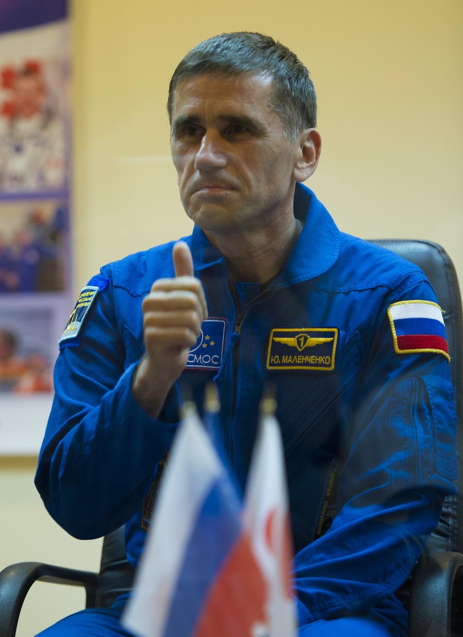Quarantined Expedition 32 Soyuz Commander Yuri Malenchenko gives the thumbs up to his family behind glass during a prelaunch press conference held at the Cosmonaut Hotel on Friday, July 13, 2012 in Baikonur, Kazakhstan. The launch of the Soyuz spacecraft with Malenchenko, NASA Flight Engineer Sunita Williams and JAXA Flight Engineer Akihiko Hoshide is scheduled for 8:40 a.m. local time on Sunday, July 15. Photo Credit (NASA/Carla Cioffi)