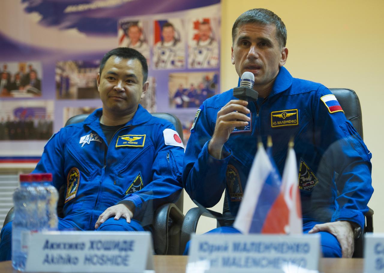 Quarantined Expedition 32 Soyuz Commander Yuri Malenchenko, right, answers reporters questions from behind glass during a prelaunch press conference held at the Cosmonaut Hotel on Friday, July 13, 2012 in Baikonur, Kazakhstan. Seated next to him is JAXA Flight Engineer Akihiko Hoshide. The launch of the Soyuz spacecraft with Malenchenko, NASA Flight Engineer Sunita Williams and Hoshide is scheduled for 8:40 a.m. local time on Sunday, July 15. Photo Credit (NASA/Carla Cioffi)