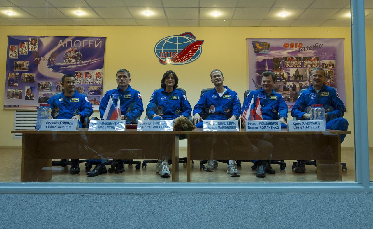 Quarantined Expedition 32 prime crew members, from left, JAXA Flight Engineer Akihiko Hoshide, Russian Soyuz Commander Yuri Malenchenko, NASA Flight Engineer Sunita Williams, along with Expedition 32 backup few members, Tom Marshburn, Roman Romanenko and Chris Hadfield prepare to answer reporters questions from behind glass during a prelaunch press conference held at the Cosmonaut Hotel on Friday, July 13, 2012 in Baikonur, Kazakhstan. The launch of the Soyuz spacecraft with Malenchenko, Williams and Hoshide is scheduled for 8:40 a.m. local time on Sunday, July 15. Photo Credit (NASA/Carla Cioffi)