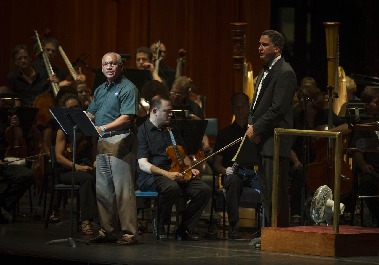 NASA Administrator Charles Bolden, left, speaks as Emil de Cou, conductor of the National Symphony Orchestra, right, looks on during a performance entitled "The Planets--An HD Odyessy", Friday evening, July 27, 2012, at the Wolf Trap National Park for the Performing Arts in Vienna, Va. Photo Credit: (NASA/Paul E. Alers)