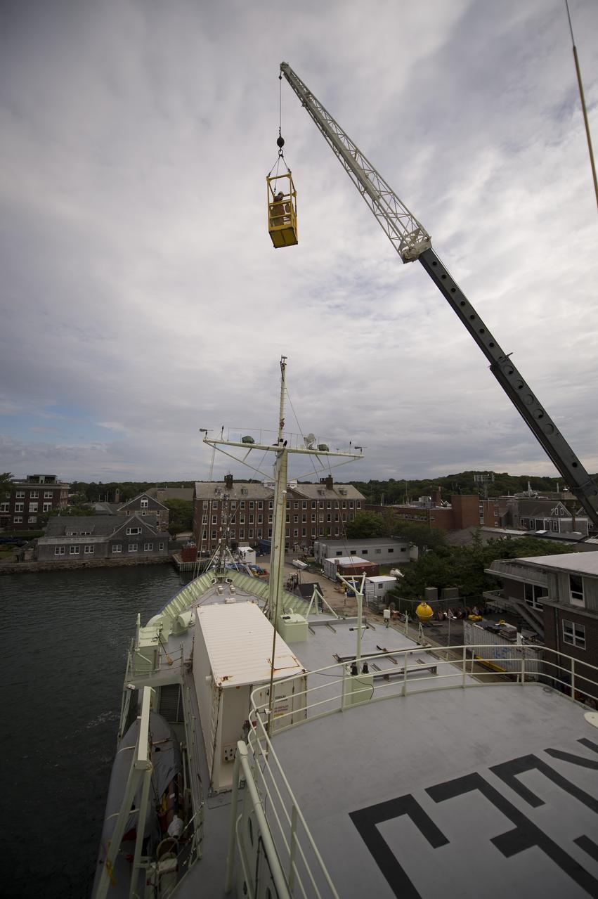 An engineer is raised by crane to work on the Woods Hole Oceanographic Institution's research vessel Knorr on Tuesday, Sept. 4, 2012, in Woods Hole, Mass. Knorr is scheduled to depart on Sept. 6 to take part in the Salinity Processes in the Upper Ocean Regional Study (SPURS). The NASA-sponsored expedition will sail to the North Atlantic's saltiest spot to get a detailed, 3-D picture of how salt content fluctuates in the ocean's upper layers and how these variations are related to shifts in rainfall patterns around the planet. Photo Credit: (NASA/Bill Ingalls)