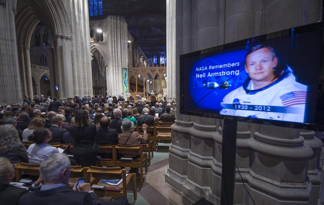 An image of Neil Armstrong is projected on a television screen as attendees sit in the Nave during a memorial service celebrating the life of Neil Armstrong at the Washington National Cathedral, Thursday, Sept. 13, 2012. Armstrong, the first man to walk on the moon during the 1969 Apollo 11 mission, died Saturday, Aug. 25. He was 82. Photo Credit: (NASA/Bill Ingalls)