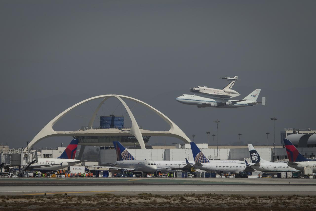 Space shuttle Endeavour, mounted atop a NASA 747 Shuttle Carrier Aircraft (SCA) performs a flyby of the Theme Building at Los Angeles International Airport, Friday, Sept. 21, 2012. Endeavour, built as a replacement for space shuttle Challenger, completed 25 missions, spent 299 days in orbit, and orbited Earth 4,671 times while traveling 122,883,151 miles. Beginning Oct. 30, the shuttle will be on display in the California Science center's Samuel Oschin Space Shuttle Endeavour  Display Pavilion, embarking on its new mission to commemorate past achievements in space and educate and inspire future generations of explorers.Photo Credit: (NASA/Scott Andrews)