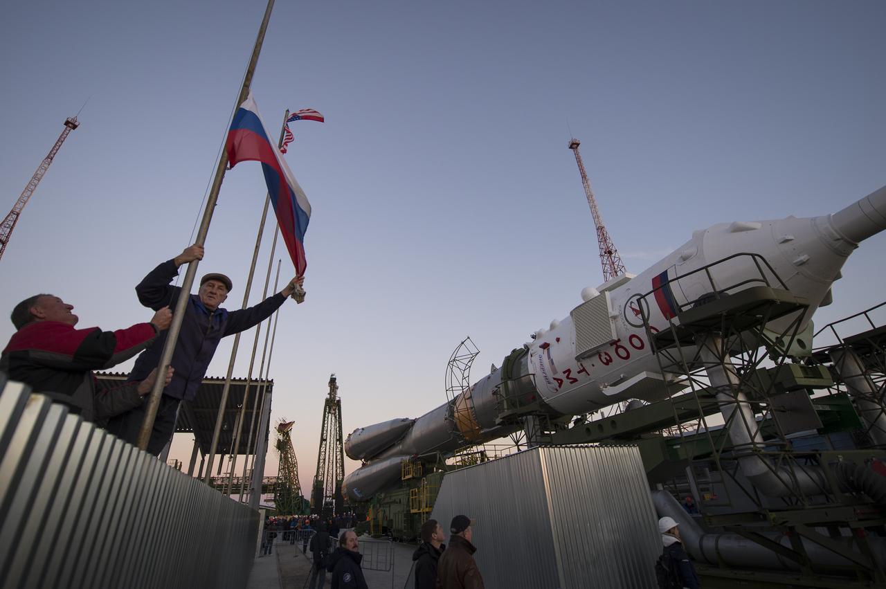 Workers raise a Russian flag as the Soyuz rocket arrives at the launch pad by train, on Sunday, October 21, 2012, at the Baikonur Cosmodrome in Kazakhstan.  Launch of the Soyuz rocket is scheduled for October 23 and will send Expedition 33/34 Flight Engineer Kevin Ford of NASA, Soyuz Commander Oleg Novitskiy and Flight Engineer Evgeny Tarelkin of ROSCOSMOS on a five-month mission aboard the International Space Station.  Photo Credit: (NASA/Bill Ingalls)