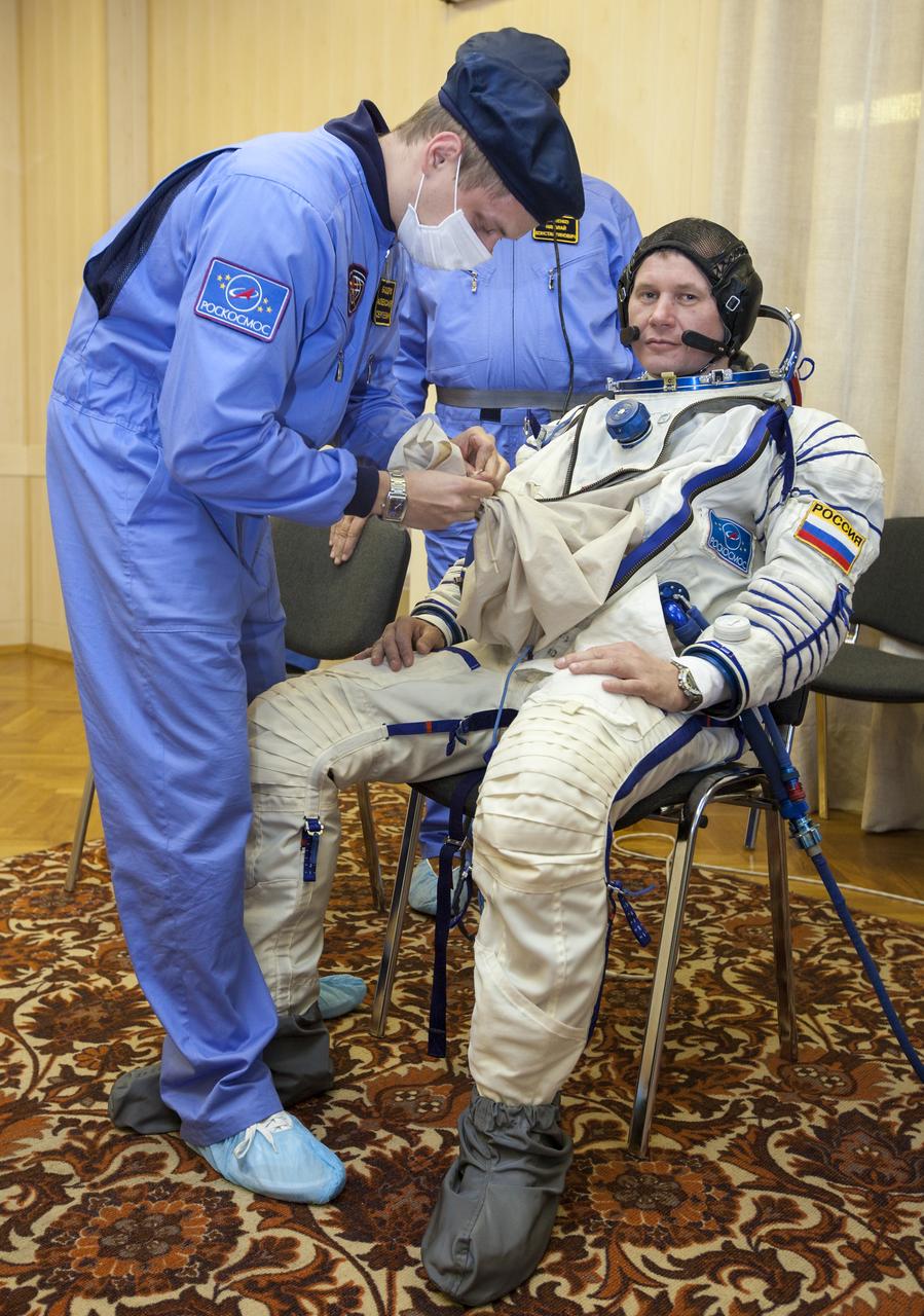 Expedition 33/34 Soyuz Commander Oleg Novitskiy is helped into his Russian Sokol suit as he and fellow cremates, Flight Engineer Kevin Ford, and Flight Engineer Evgeny Tarelkin prepare for their Soyuz launch to the International Space Station, on Tuesday, October 23, 2012, in Baikonur, Kazakhstan. Launch of the Soyuz rocket will send Ford, Novitskiy and Tarelkin on a five-month mission aboard the International Space Station.  Photo Credit: (NASA/GCTC/Andrey Shelepin)