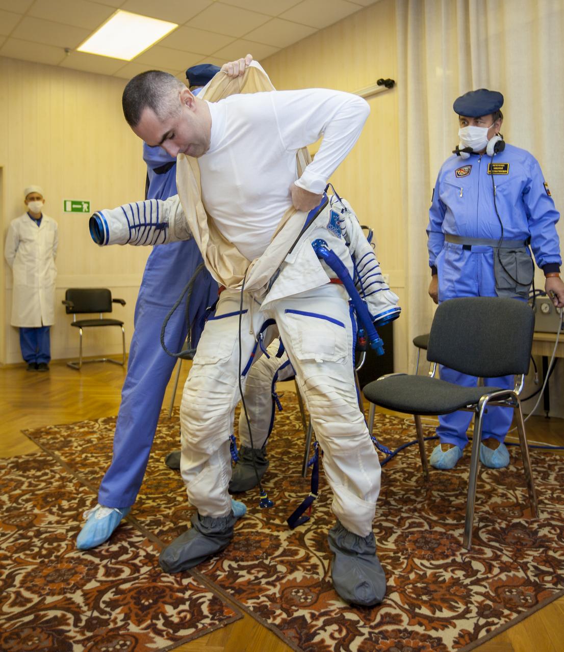 Expedition 33/34 Flight Engineer Evgeny Tarelkin is helped into his Russian Sokol suit as he and fellow cremates, Soyuz Commander Oleg Novitskiy, and Flight Engineer Kevin Ford prepare for their Soyuz launch to the International Space Station, on Tuesday, October 23, 2012, in Baikonur, Kazakhstan. Launch of the Soyuz rocket will send Ford, Novitskiy and Tarelkin on a five-month mission aboard the International Space Station. Photo Credit: (NASA/GCTC/Andrey Shelepin)