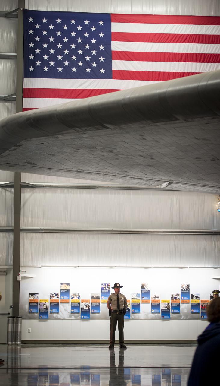 A police officer is seen underneath the wing of the space shuttle Endeavour during the grand opening ceremony for the California Science center's Samuel Oschin Space Shuttle Endeavour Display Pavilion, Tuesday, Oct. 30, 2012, in Los Angeles.  Endeavour, built as a replacement for space shuttle Challenger, completed 25 missions, spent 299 days in orbit, and orbited Earth 4,671 times while traveling 122,883,151 miles. Photo Credit: (NASA/Bill Ingalls)