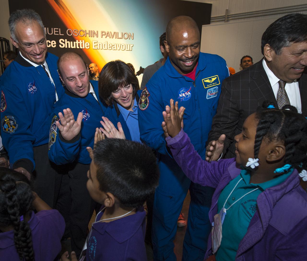 NASA Astronauts, from left, Danny Olivas, Garrett Reisman, Barbara Morgan, and, NASA Associate Administrator for Education and Astronaut, Leland Melvin give high fives to school children as they enter the California Science center's Samuel Oschin Space Shuttle Endeavour Display Pavilion, Tuesday, Oct. 30, 2012, in Los Angeles.  Endeavour, built as a replacement for space shuttle Challenger, completed 25 missions, spent 299 days in orbit, and orbited Earth 4,671 times while traveling 122,883,151 miles. Photo Credit: (NASA/Bill Ingalls)