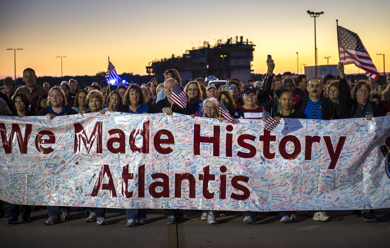 Workers carry a banner full of signatures while following behind space shuttle Atlantis as it begins its trek to its new home at the Kennedy Space Center Visitor Complex, early Friday, Nov. 2, 2012, in Cape Canaveral, Fla.  The spacecraft traveled 125,935,769 miles during 33 spaceflights, including 12 missions to the International Space Station. Its final flight, STS-135, closed out the Space Shuttle Program era with a landing on July 21, 2011. Photo Credit: (NASA/Bill Ingalls)