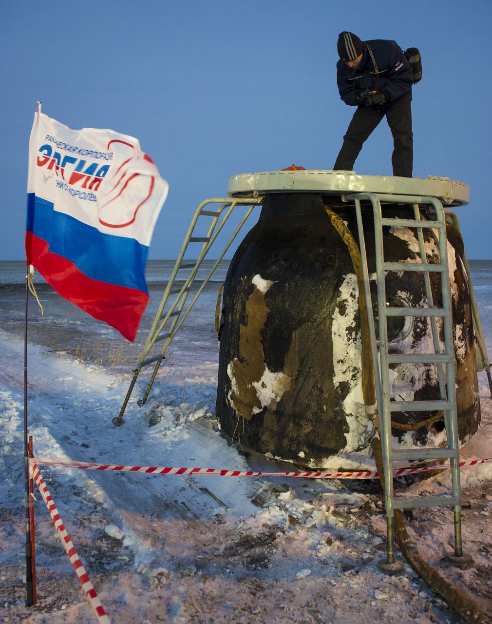 A photographer stands atop the Soyuz TMA-05M spacecraft long after it landed with Expedition 33 Commander Sunita Williams of NASA and Flight Engineers Akihiko Hoshide of JAXA (Japan Aerospace Exploration Agency), and Yuri Malenchenko of ROSCOSMOS (Russian Federal Space Agency) in a remote area near the town of Arkalyk, Kazakhstan, on Monday, Nov. 19, 2012. Williams, Hoshide and Malenchenko returned from four months onboard the International Space Station. Photo Credit: (NASA/GCTC/Andrey Shelepin)
