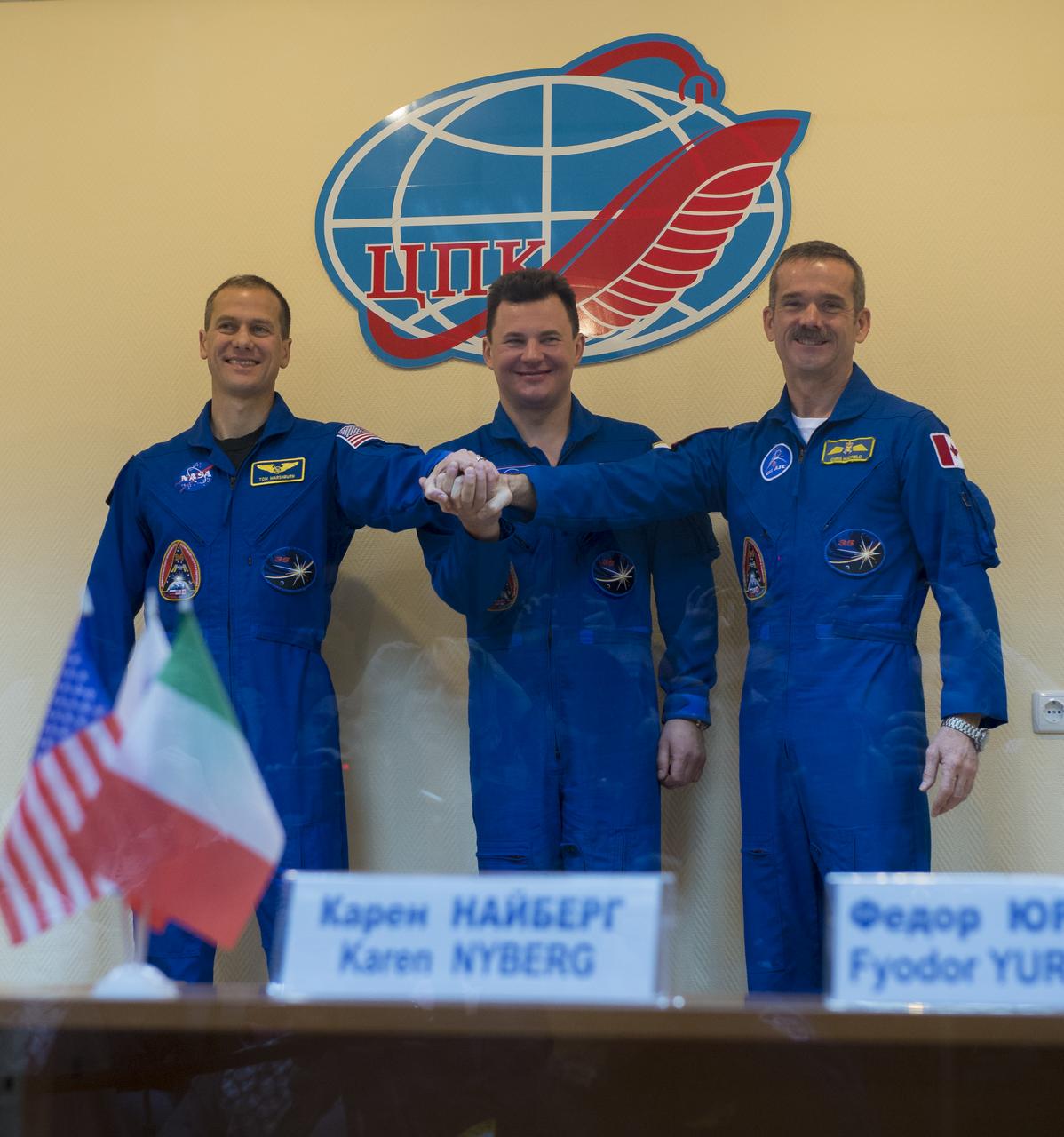 Expedition 34/35 Flight Engineer Tom Marshburn of NASA, left, Soyuz Commander Roman Romanenko and Canadian Space Agency (CSA) Flight Engineer Chris Hadfield, right, pose for a photo at a press conference held at the Cosmonaut Hotel, on Tuesday, Dec. 18, 2012, in Baikonur, Kazakhstan. Launch of the Soyuz rocket is scheduled for December 19 and will send Marshburn, Romanenko and Hadfield on a five-month mission aboard the International Space Station.  Photo Credit: (NASA/Carla Cioffi)
