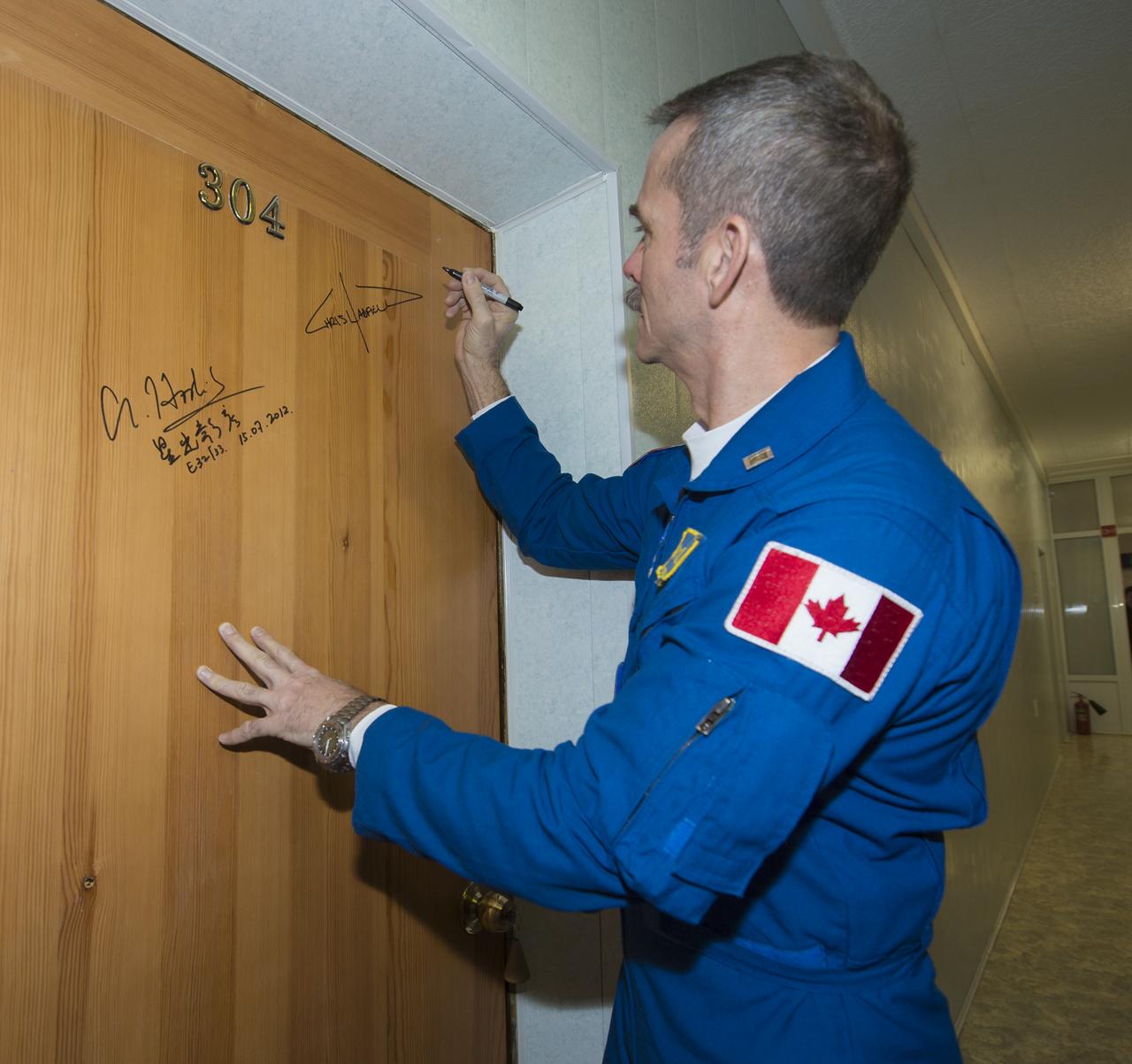 Expedition 34/35 Flight Engineer and Expedition 35 ISS Commander Chris Hadfield, of the Canadian Space Agency (CSA), performs the traditional door signing before he and fellow cremates, Flight Engineer Tom Marshburn, and Soyuz Commander Roman Romanenko depart the Cosmonaut Hotel for their Soyuz launch to the International Space Station on Wednesday, Dec. 19, 2012, in Baikonur, Kazakhstan. Launch of the Soyuz rocket will send Hadfield, Romanenko and Marshburn on a five-month mission aboard the International Space Station. Photo Credit: (NASA/Carla Cioffi)