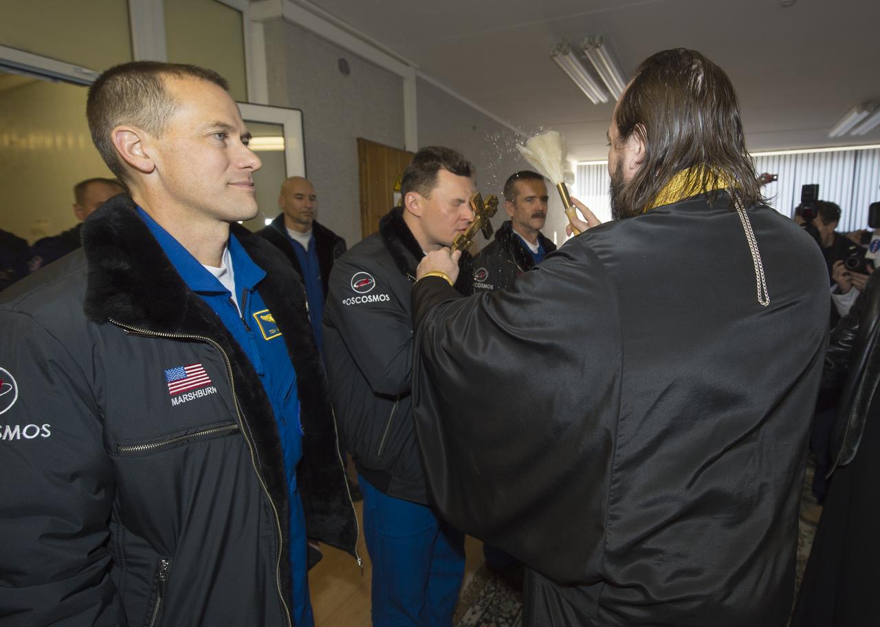 Expedition 34/35 crew members, Flight Engineer Tom Marshburn of NASA, left, Soyuz Commander Roman Romanenko, and Flight Engineer Chris Hadfield of the Canadian Space Agency (CSA), right, receive the traditional blessing from a Russian Orthodox priest at the Cosmonaut Hotel on the morning of their Soyuz launch to the International Space Station on Wednesday, Dec. 19, 2012, in Baikonur, Kazakhstan. Launch of a Soyuz rocket later in the afternoon will send Marshburn, Romanenko and Hadfield on a five-month mission aboard the International Space Station. Photo Credit: (NASA/Carla Cioffi)