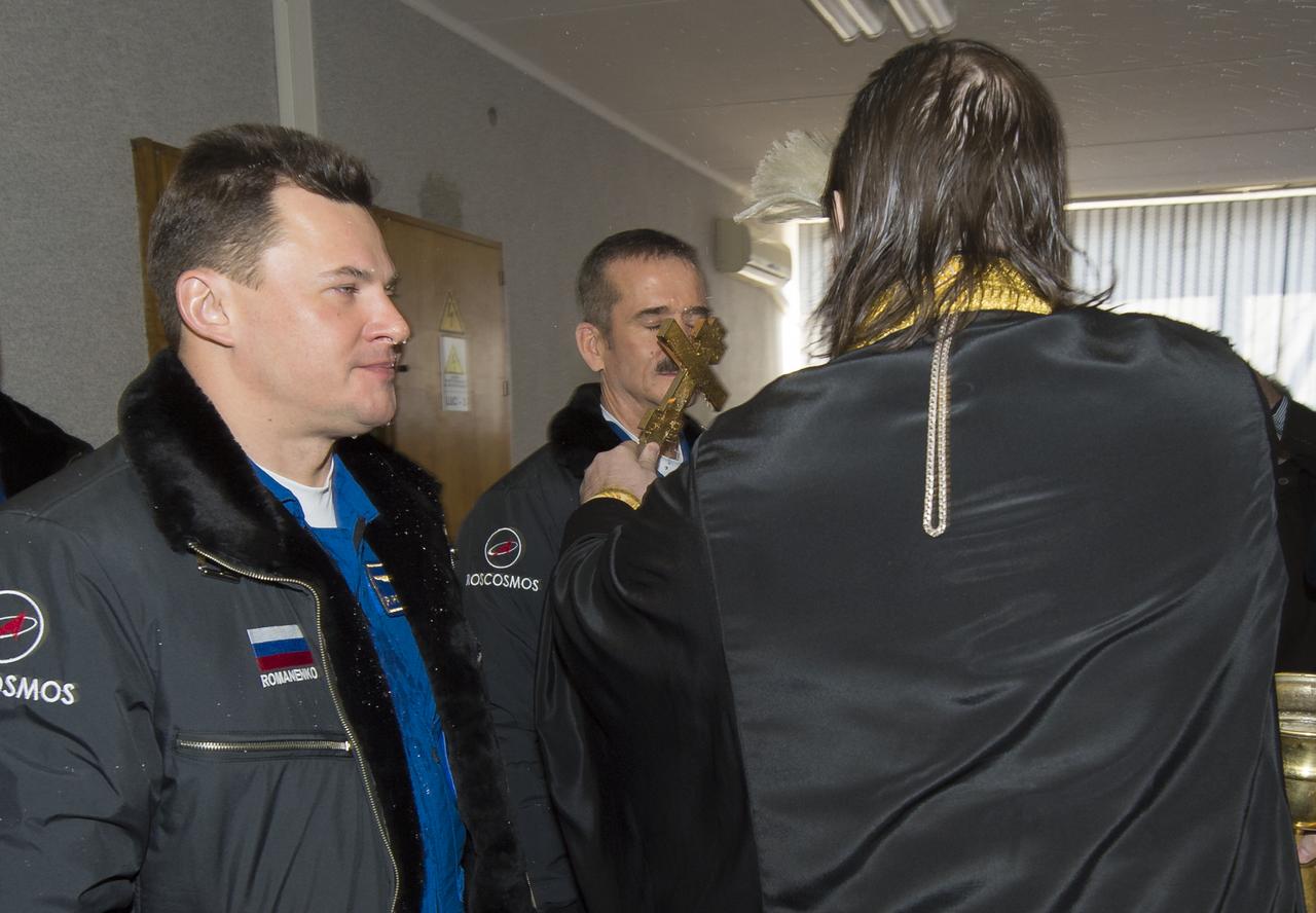 Expedition 34/35 Flight Engineer Chris Hadfield of the Canadian Space Agency (CSA), right,  receives the traditional blessing from a Russian Orthodox priest at the Cosmonaut Hotel on the morning of their Soyuz launch to the International Space Station on Wednesday, Dec. 19, 2012, in Baikonur, Kazakhstan. Launch of a Soyuz rocket later in the afternoon will send Hadfield, Roman Romanenko of Russia and Tom Marschburn of the United States on a five-month mission aboard the International Space Station.  Photo Credit: (NASA/Carla Cioffi)