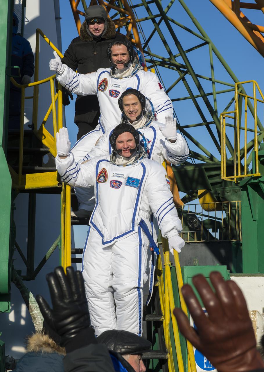 Expedition 34 NASA Flight Engineer Chris Hadfield of the Canadian Space Agency (CSA), top, NASA Flight Engineer Tom Marshburn and Soyuz Commander Roman Romanenko wave farewell from the bottom of the Soyuz rocket at the Baikonur Cosmodrome in Baikonur, Kazakhstan, Wednesday, Dec. 19, 2012.  Their Soyuz TMA-07M rocket launched at 6:12 p.m. local time.  Photo Credit: (NASA/Carla Cioffi)