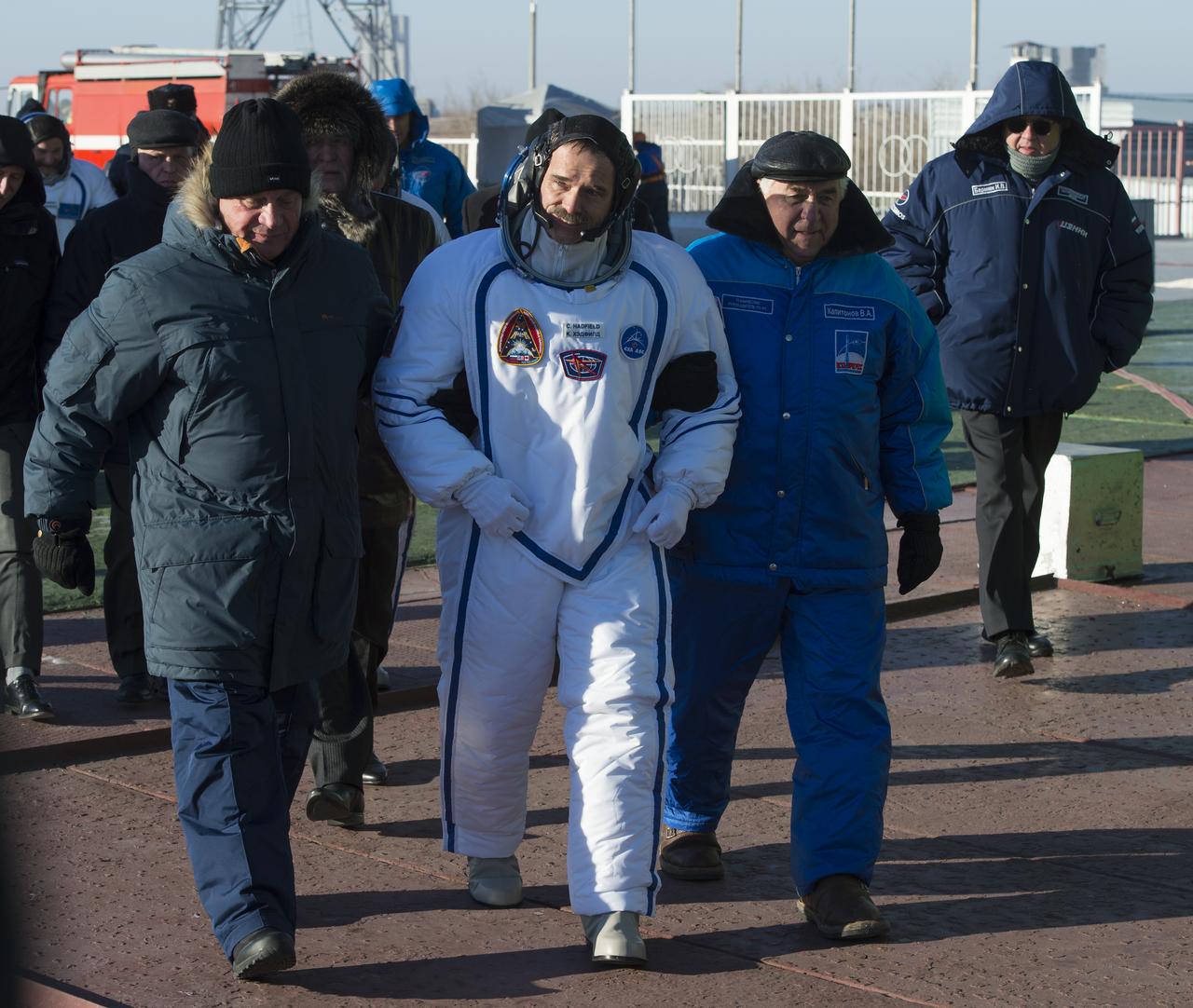 Expedition 34/35 Canadian Space Agency astronaut and Expedition 35 Commander Chris Hadfield is escorted to the Soyuz rocket by Russian Space Agency Officials, prior to his launch onboard a Soyuz TMA-07M spacecraft with fellow crew members, Russian Cosmonaut and Soyuz Commander Roman Romanenko, and, NASA astronaut and Flight Engineer Tom Marshburn, Wednesday, Dec. 19, 2012, in Baikonur, Kazakhstan. Launch of the Soyuz rocket will send Hadfield, Romanenko and Marshburn on a five-month mission aboard the International Space Station.  Photo Credit: (NASA/Carla Cioffi)