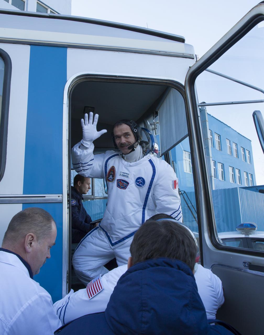 Expedition 34/35 Flight Engineer Chris Hadfield of the Canadian Space Agency (CSA) waves goodbye as he boards the bus that will take him to the launch pad where he and his fellow crew mates will board their Soyuz TMA-07M rocket, on Wednesday, Dec. 19, 2012, in Baikonur, Kazakhstan. The crew are donning special cold-weather suits over their Sokol suits to keep them insulated from the extreme sub-zero temperature.  Launch of the Soyuz rocket will send Hadfield, Romanenko and Marshburn on a five-month mission aboard the International Space Station.  Photo Credit: (NASA/Victor Zelentsov)