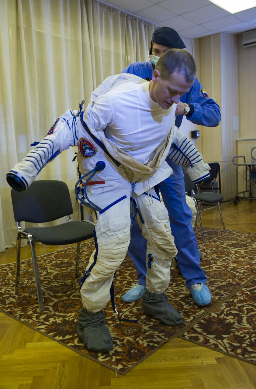 Expedition 34/35 Soyuz NASA Flight Engineer Tom Marshburn is helped into his Russian Sokol suit as he and fellow cremates, Soyuz Commander Roman Romanenko and Flight Engineer Chris Hadfield prepare for their Soyuz launch to the International Space Station, on Wednesday, Dec. 19, 2012, in Baikonur, Kazakhstan. Launch of the Soyuz rocket will send Marshburn, Romanenko and Hadfield on a five-month mission aboard the International Space Station. Photo Credit: (NASA/GCTC/Andrey Shelepin)