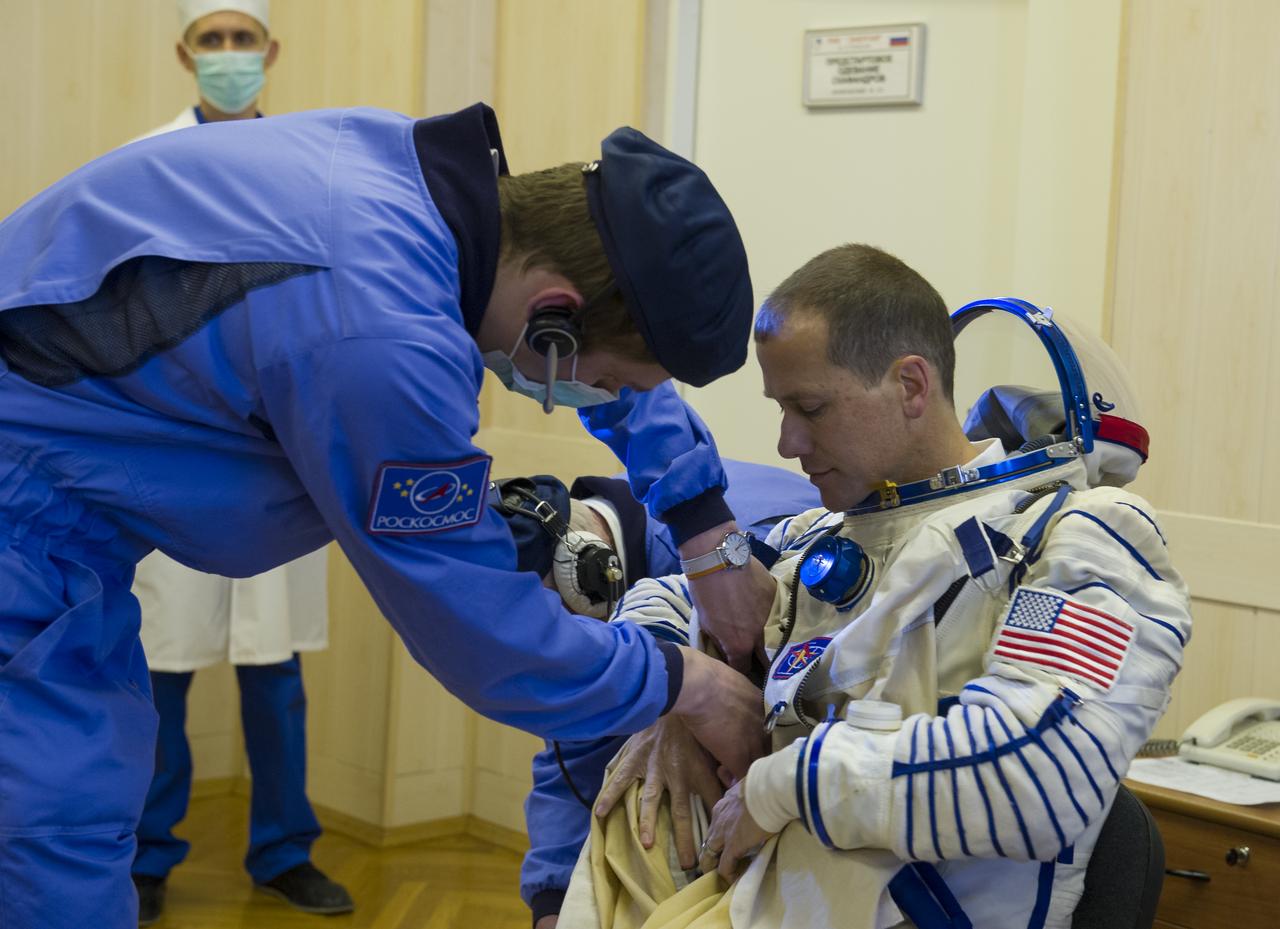 Expedition 34/35 Soyuz NASA Flight Engineer Tom Marshburn is helped into his Russian Sokol suit as he and fellow cremates, Soyuz Commander Roman Romanenko and Flight Engineer Chris Hadfield prepare for their Soyuz launch to the International Space Station, on Wednesday, Dec. 19, 2012, in Baikonur, Kazakhstan. Launch of the Soyuz rocket will send Marshburn, Romanenko and Hadfield on a five-month mission aboard the International Space Station. Photo Credit: (NASA/GCTC/Andrey Shelepin)