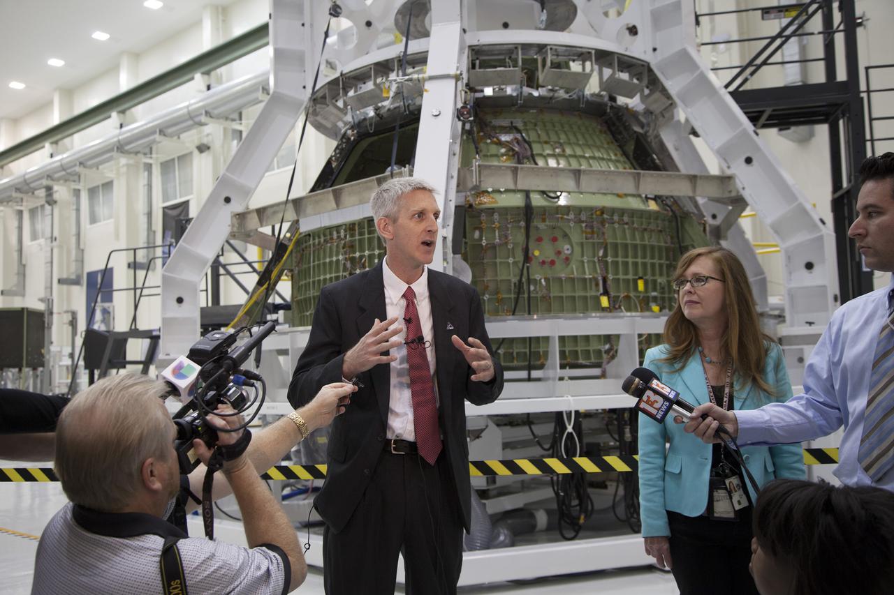 CAPE CANAVERAL, Fla. – Inside the high bay of Kennedy Space Center's Operations and Checkout Building, Scott Wilson, NASA's Orion production manager at the Florida Spaceport, briefs members of the news media about progress in preparing Orion for its first flight. In the background, the Orion spacecraft is surrounded by a special pre-launch processing access fixture.   Orion is the exploration spacecraft designed to carry crews to space beyond low Earth orbit. It will provide emergency abort capability, sustain the crew during the space travel and provide safe re-entry from deep space return velocities. The first unpiloted test flight of the Orion is scheduled to launch in 2014 atop a Delta IV rocket and in 2017 on a Space Launch System rocket. For more information, visit http:__www.nasa.gov_orion Photo credit: NASA_Kim Shiflett