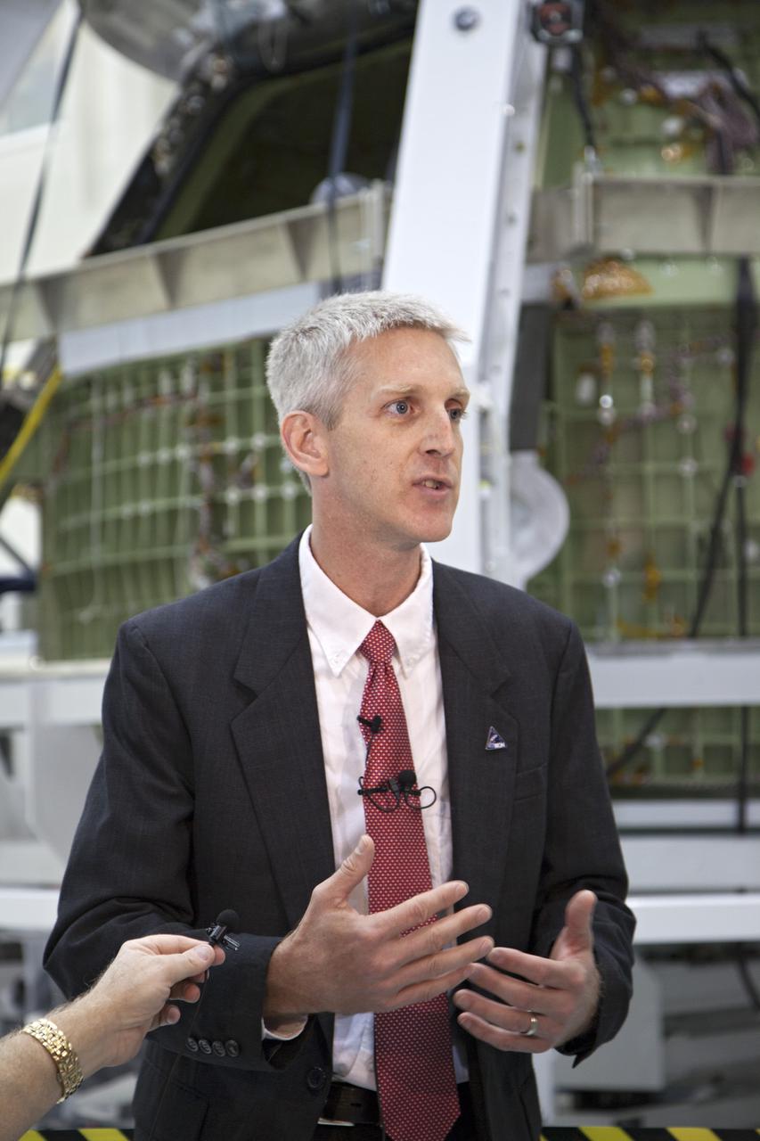 CAPE CANAVERAL, Fla. – Inside the high bay of Kennedy Space Center's Operations and Checkout Building, Scott Wilson, NASA's Orion production manager at the Florida Spaceport, briefs members of the news media about progress in preparing Orion for its first flight. In the background, the Orion spacecraft is surrounded by a special pre-launch processing access fixture.   Orion is the exploration spacecraft designed to carry crews to space beyond low Earth orbit. It will provide emergency abort capability, sustain the crew during the space travel and provide safe re-entry from deep space return velocities. The first unpiloted test flight of the Orion is scheduled to launch in 2014 atop a Delta IV rocket and in 2017 on a Space Launch System rocket. For more information, visit http:__www.nasa.gov_orion Photo credit: NASA_Kim Shiflett