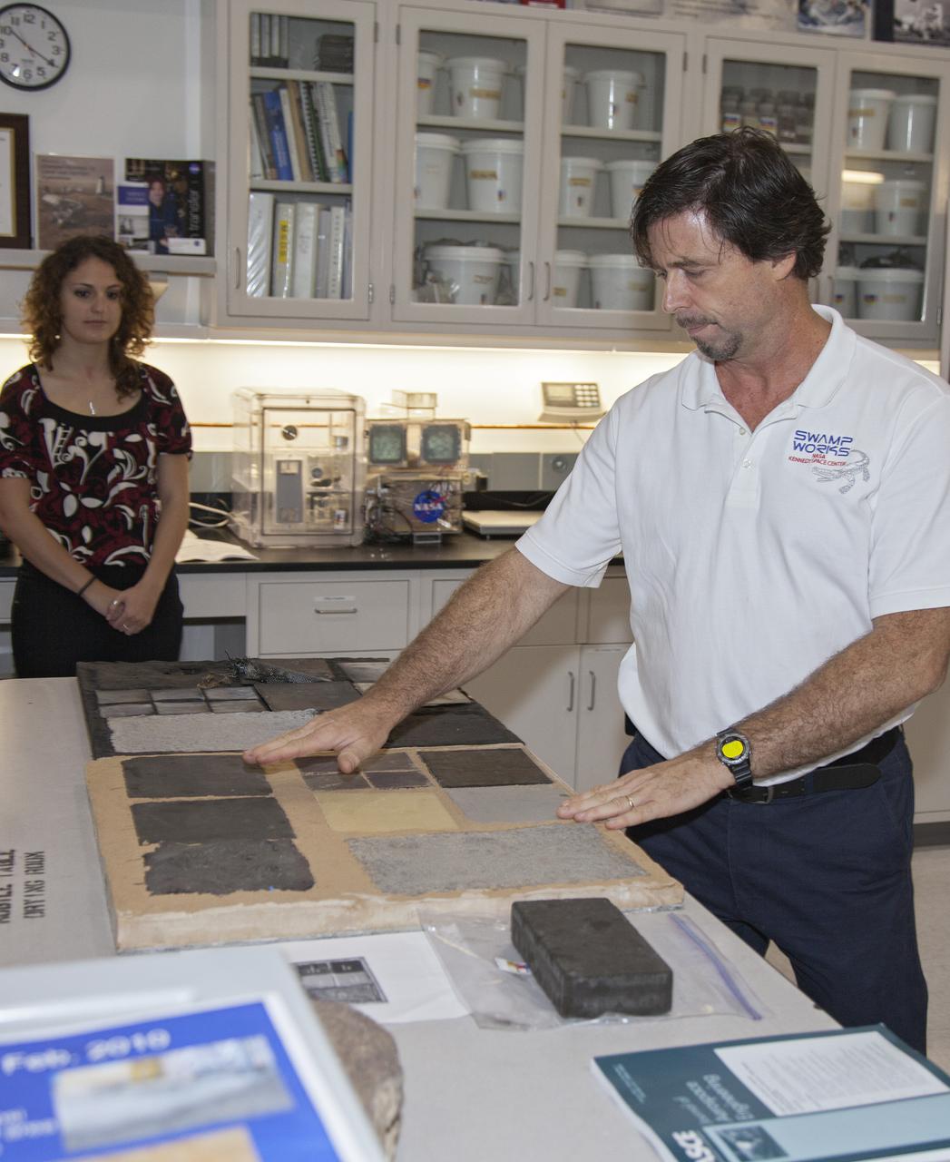 CAPE CANAVERAL, Fla. -- Dr. Phil Metzger, at right, a principal investigator in the Surface Systems Office, discusses some of NASA's cutting-edge projects with media representatives touring the Granular Mechanics and Regolith Operations, or GMRO, Lab in the Swamp Works at NASA's Kennedy Space Center in Florida. The GMRO team develops robotics to excavate regolith and ice as resources and to prepare berms, roads and landing pads. The laboratory also studies the physics of blowing rego¬lith and other materials in a rocket exhaust plume to predict and mitigate the blast effects of launches and landings.  The team performed a demonstration of the Regolith Advanced Surface Systems Operations Robot, or RASSOR, for the media.    Kennedy's Swamp Works provides rapid, innovative and cost-effective exploration mission solutions, leveraging partnerships across NASA, industry and academia. Kennedy's research and technology mission is to improve spaceports on Earth, as well as lay the groundwork for establishing spaceports at destinations in space. For more information, visit http:__www.nasa.gov_centers_kennedy_exploration_researchtech_index.html.  Photo credit: NASA_Frankie Martin