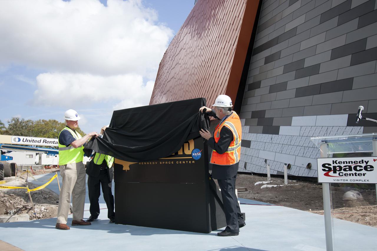 CAPE CANAVERAL, Fla. -- From the left, former NASA astronaut Jon McBride, Rick Abramson, president of Delaware North Companies Parks and Resorts partially hidden, and Bill Moore, chief operating officer of the visitor complex, unveil the Atlantis exhibit's newly designed logo. Last November, the space shuttle Atlantis made its historic final journey to its new home, traveling 10 miles from the Kennedy Space Center's Vehicle Assembly Building to the spaceport's visitor complex. The new $100 million Atlantis facility will be a 90,000-square-foot, interactive exhibit that tells the story of the 30-year Space Shuttle Program and highlights the future of space exploration. Photo credit: NASA_Jim Grossmann