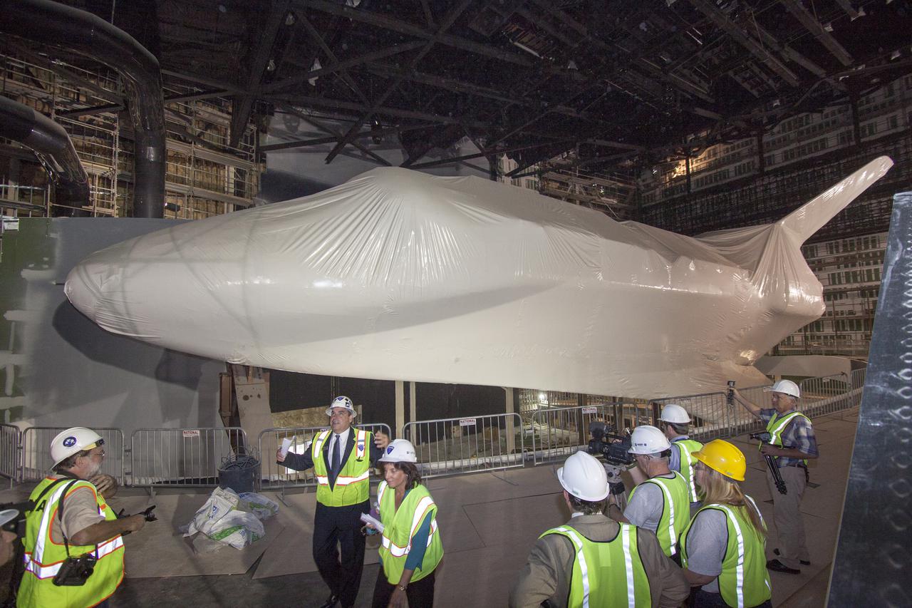 CAPE CANAVERAL, Fla. -- Tim Macy, Delaware North Companies Parks and Resorts director of project development, described the Atlantis exhibit to members of the news media who media gather at the Kennedy Space Center Visitor Complex for the announcement of the opening date of the date the facility will officially open and for the unveiling of the exhibit's newly designed logo. The space shuttle is wrapped in plastic to protect it during completion of construction. The 'Space Shuttle Atlantis' exhibit will open June 29, 2013.  Last November, the space shuttle Atlantis made its historic final journey to its new home, traveling 10 miles from the Kennedy Space Center's Vehicle Assembly Building to the spaceport's visitor complex. The new $100 million Atlantis facility will be a 90,000-square-foot, interactive exhibit that tells the story of the 30-year Space Shuttle Program and highlights the future of space exploration. Photo credit: NASA_Jim Grossmann