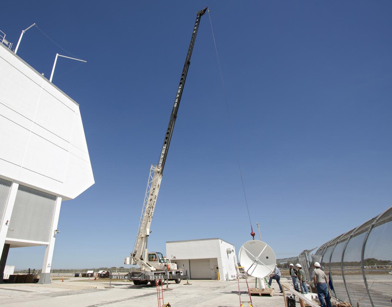 CAPE CANAVERAL, Fla. – Workers use a crane to install a new parabolic telemetry antenna and tracker camera to the roof of the Launch Control Center, or LCC, in Launch Complex 39 at NASA's Kennedy Space Center in Florida. This antenna and camera system is the first of three that will be installed on the LCC roof for the Radio Frequency and Telemetry Station RFTS, which will be used to monitor radio frequency communications from a launch vehicle at Launch Pad 39A or B as well as provide radio frequency relay for a launch vehicle in the Vehicle Assembly Building. The RFTS replaces the shuttle-era communications and tracking labs at Kennedy. The modern RFTS checkout station is designed to primarily support NASA's Space Launch System, or SLS, and Orion spacecraft, but can support multi-user radio frequency tests as the space center transitions to support a variety of rockets and spacecraft.      For more information on the modernization efforts at Kennedy, visit the Ground Systems Development and Operations, or GSDO, website at http:__go.nasa.gov_groundsystems. Photo credit: NASA_Jim Grossmann