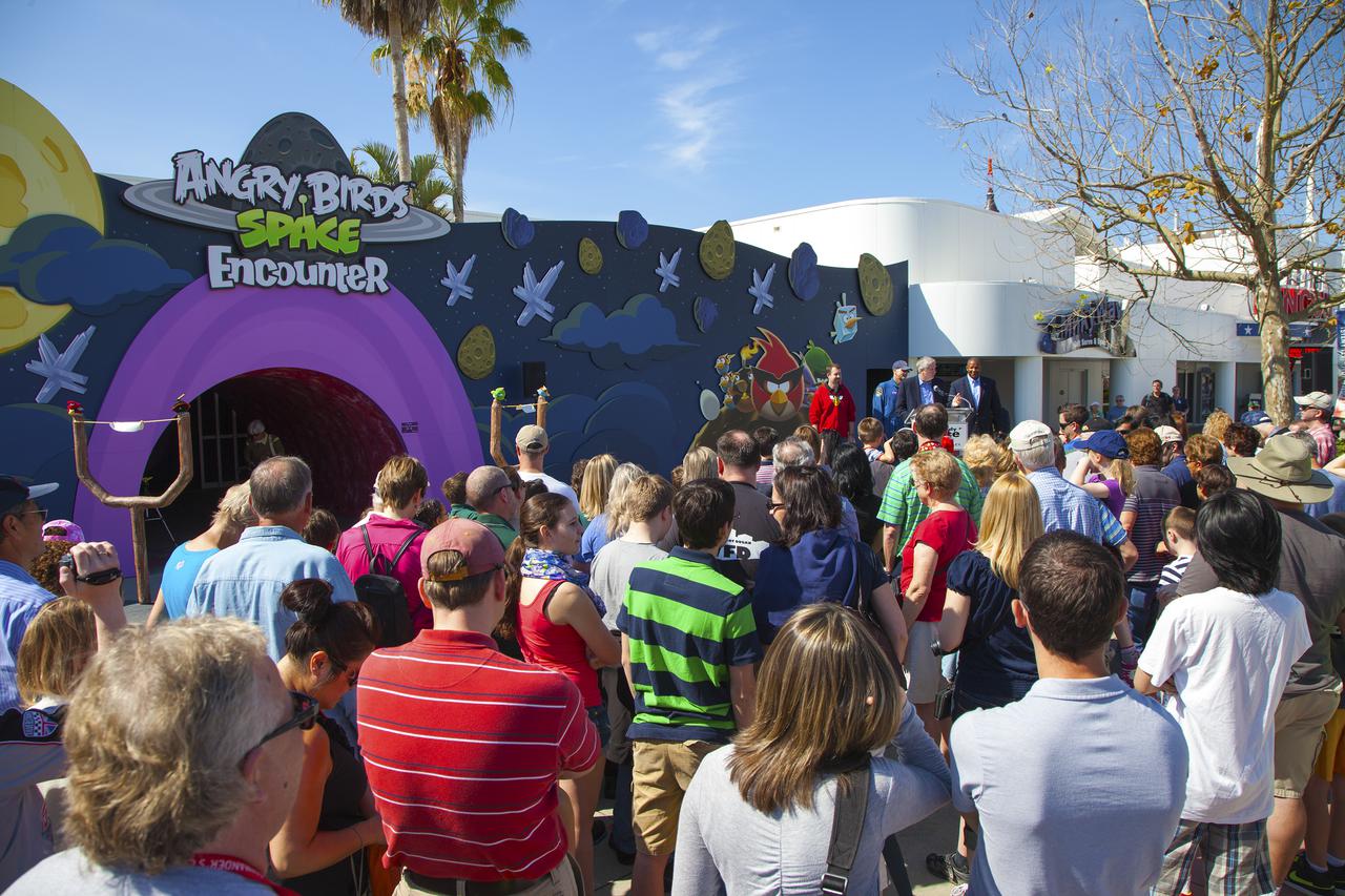 CAPE CANAVERAL, Fla. -- At NASA’s Kennedy Space Center Visitor Complex in Florida, a crowd of people gather for the grand opening of the new Angry Birds Space Encounter. On stage, from left are Dan Mitchell, director of location-based entertainment with Rovio Entertainment Bill Moore, chief operating officer with the KSC visitor complex and Kelvin Manning, associate deputy director of Kennedy Space Center. Standing behind Moore is NASA astronaut Don Pettit.  Finland-based Rovio Entertainment, the creator of the Angry Birds Space game, partnered with Kennedy Space Center to bring the beloved characters to life. It is the first Angry Birds interactive exhibit in the United States designed for people of all ages. The 4,485-square-foot facility hosts the space adventures of the Angry Birds as they travel into an intergalactic wormhole, come face-to-face with Space Pigs and discover heroic superpowers. Six interactive stations are designed to encourage children in science, technology, engineering and mathematics fields of study. Photo credit: NASA_Kim Shiflett