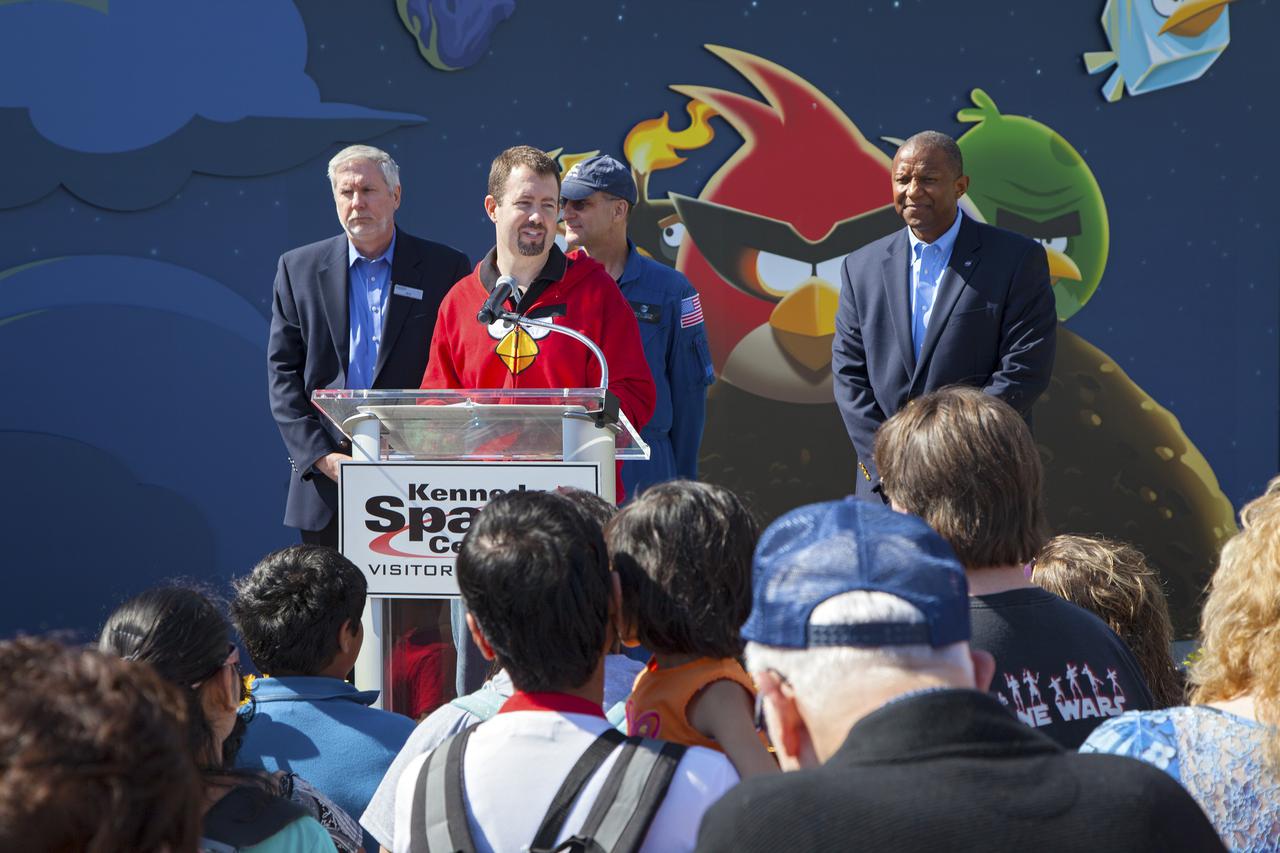CAPE CANAVERAL, Fla. -- At NASA’s Kennedy Space Center Visitor Complex in Florida, Dan Mitchell, director of location-based entertainment for Rovio Entertainment, speaks to visitors during the grand opening of the new Angry Birds Space Encounter. Standing behind Mitchell, from left are Bill Moore, chief operating officer with the KSC visitor complex NASA astronaut Don Pettit and Kelvin Manning, associate deputy director of Kennedy Space Center.  Finland-based Rovio Entertainment, the creator of the Angry Birds Space game, partnered with Kennedy Space Center to bring the beloved characters to life. It is the first Angry Birds interactive exhibit in the United States designed for people of all ages. The 4,485-square-foot facility hosts the space adventures of the Angry Birds as they travel into an intergalactic wormhole, come face-to-face with Space Pigs and discover heroic superpowers. Six interactive stations are designed to encourage children in science, technology, engineering and mathematics fields of study. Photo credit: NASA_Kim Shiflett