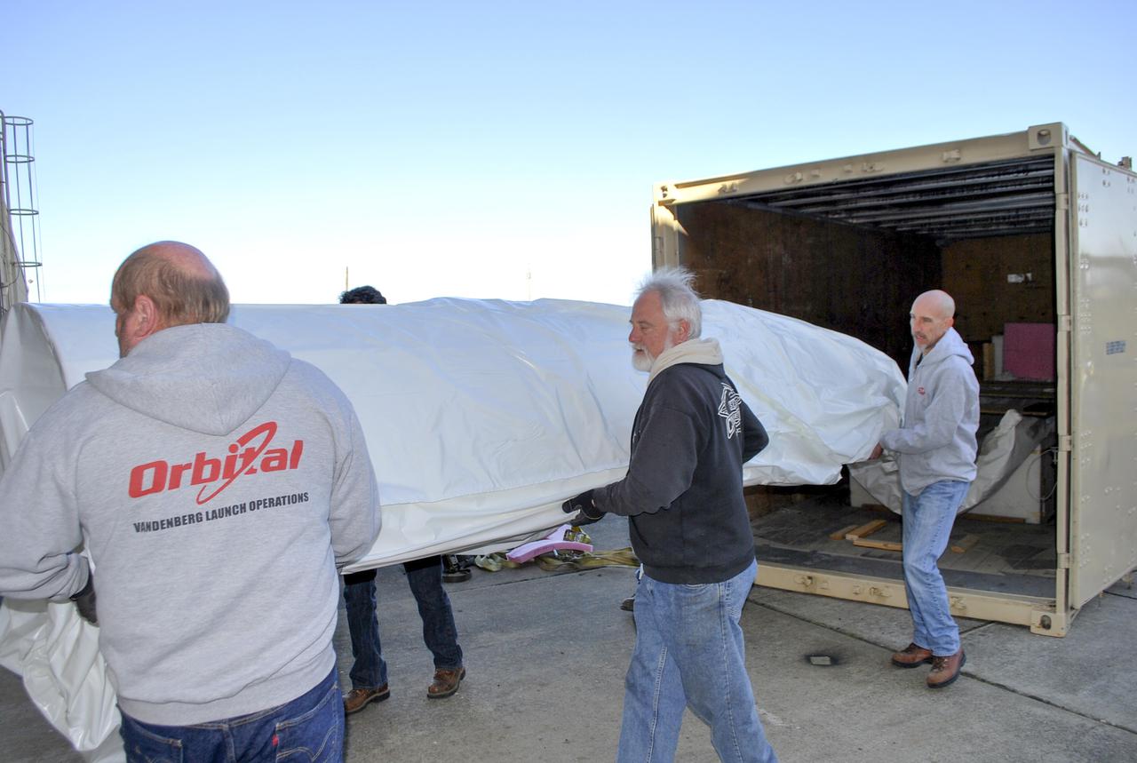 VANDENBERG AFB, Calif. – Workers carry half of a payload fairing into a hangar at Vandenberg Air Force Base in California where it will be processed and used for NASA's IRIS mission. The fairing will be fitted to the nose of an Orbital Sciences Pegasus rocket and will protect the IRIS spacecraft from atmospheric heating and stress during launch. Photo credit: VAFB_Randy Beaudoin