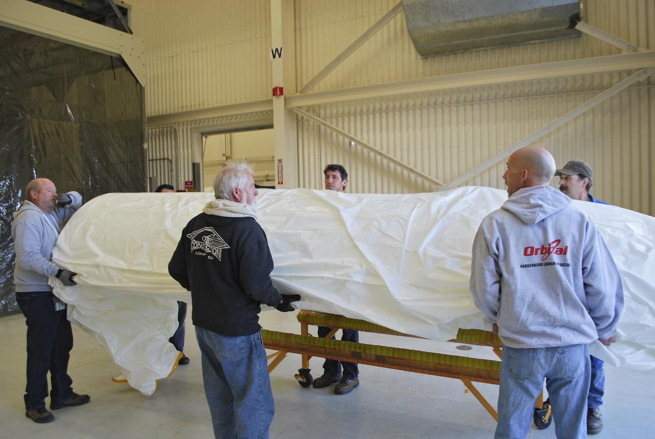 VANDENBERG AFB, Calif. – Workers load half of a payload fairing inside a hangar at Vandenberg Air Force Base in California where it will be processed and used for NASA's IRIS mission. The fairing will be fitted to the nose of an Orbital Sciences Pegasus rocket and will protect the IRIS spacecraft from atmospheric heating and stress during launch. Photo credit: VAFB_Randy Beaudoin