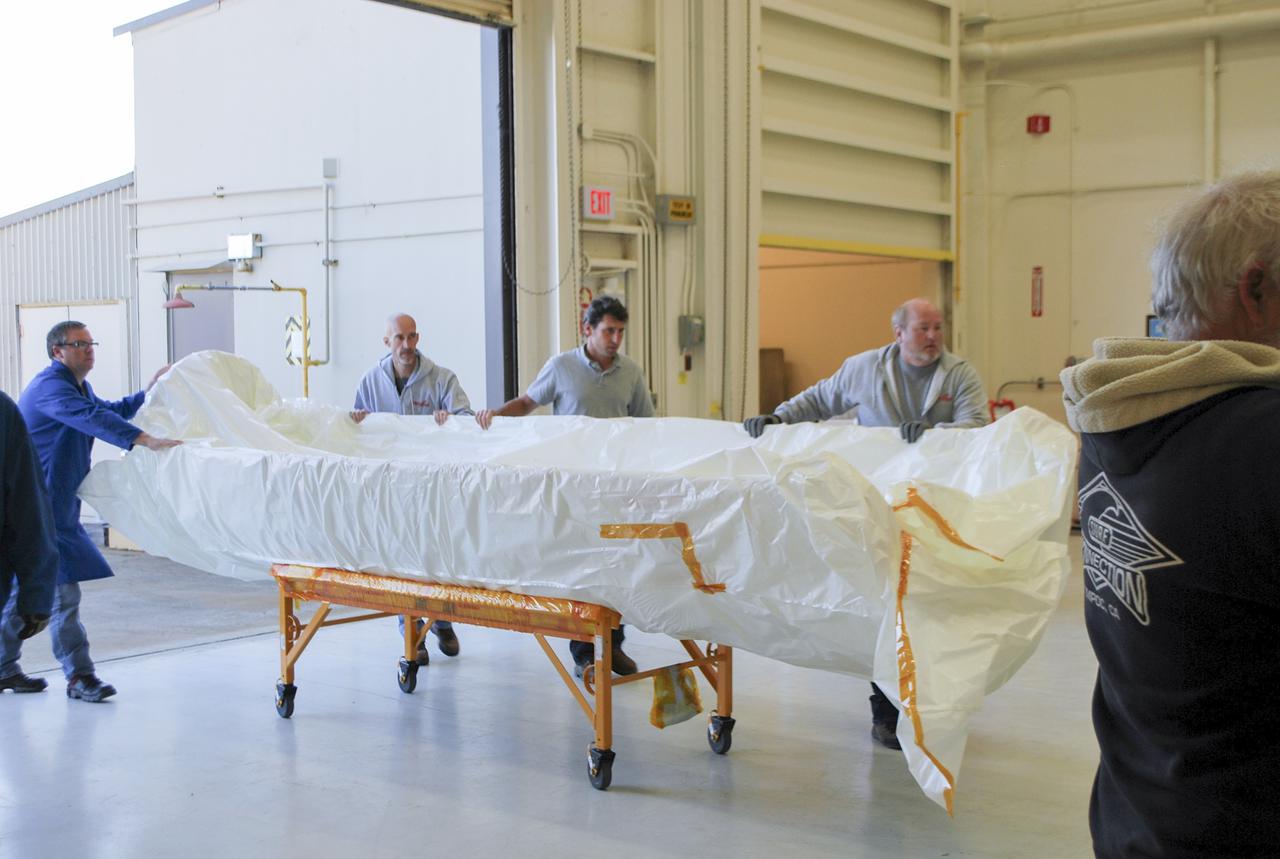 VANDENBERG AFB, Calif. – Workers load half of a payload fairing inside a hangar at Vandenberg Air Force Base in California where it will be processed and used for NASA's IRIS mission. The fairing will be fitted to the nose of an Orbital Sciences Pegasus rocket and will protect the IRIS spacecraft from atmospheric heating and stress during launch. Photo credit: VAFB_Randy Beaudoin
