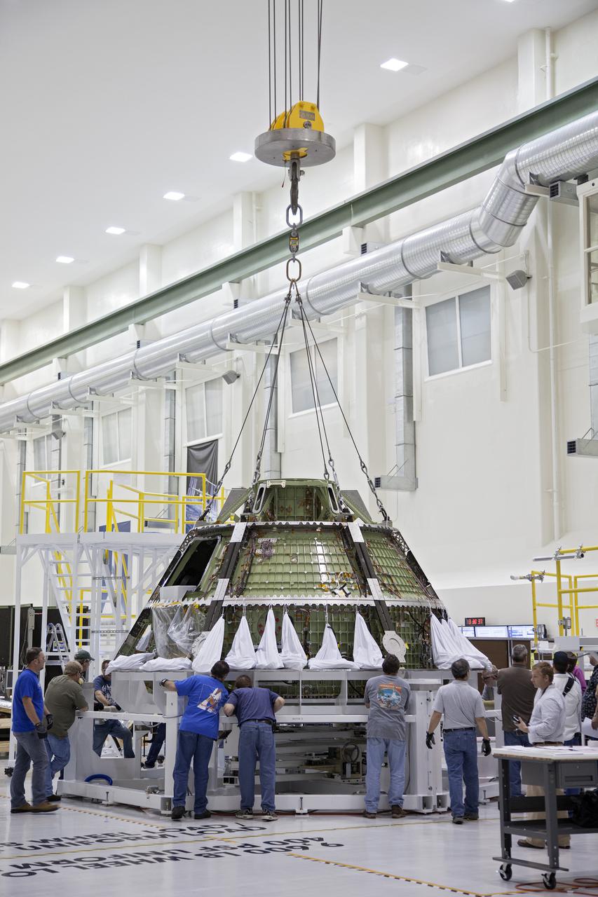 CAPE CANAVERAL, Fla. -- Inside the Operations and Checkout Building high bay at NASA’s Kennedy Space Center in Florida, workers monitor the progress as a crane begins to lift the Orion crew module from its processing stand and transfer it to a dolly. Orion is being prepared for Exploration Flight Test 1, or EFT-1. Orion is the exploration spacecraft designed to carry crews to space beyond low Earth orbit. It will provide emergency abort capability, sustain the crew during the space travel and provide safe re-entry from deep space return velocities. Orion’s first unpiloted test flight is scheduled to launch in 2014 atop a United Launch Alliance Delta IV heavy rocket. A second uncrewed flight test is scheduled for 2017 on the Space Launch System rocket. For more information, visit http:__www.nasa.gov_orion. Photo credit: NASA_Frankie Martin